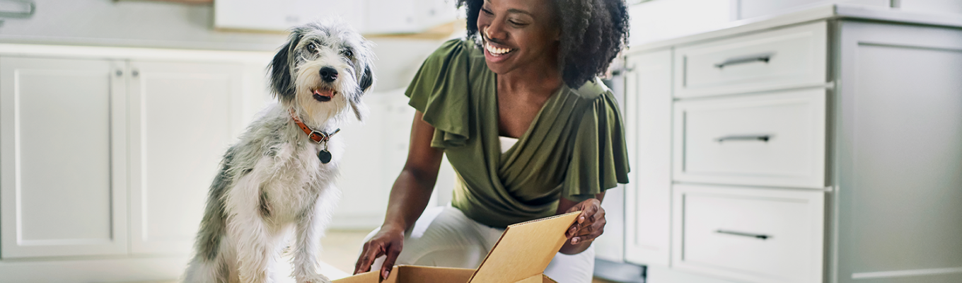 A woman opening a box and smiling at her dog