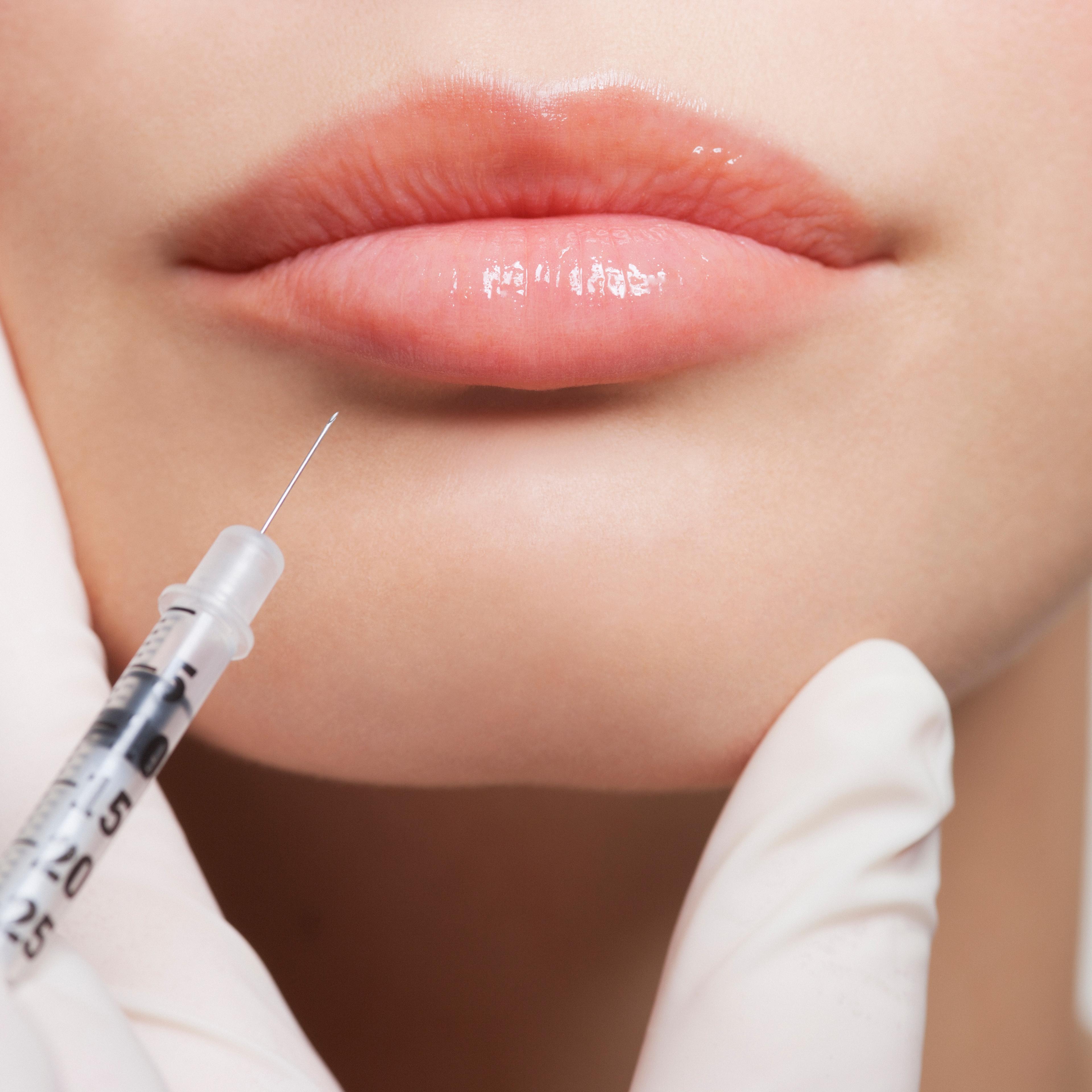 Close up of woman receiving botox injection in lips