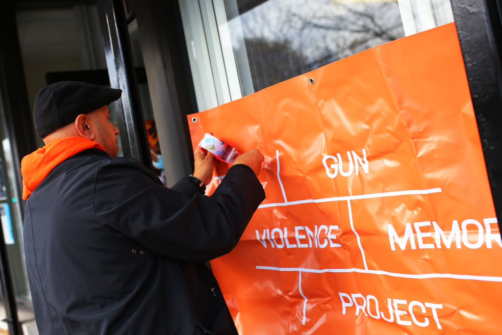 Jason Rodriguez, outreach supervisor with Lifecamp, hangs a banner as families of victims of gun violence gather at Where Do We Go From Here to drop of memorabilia for the Gun Violence Memorial Project on November 11, 2021 in Queens, NYC.