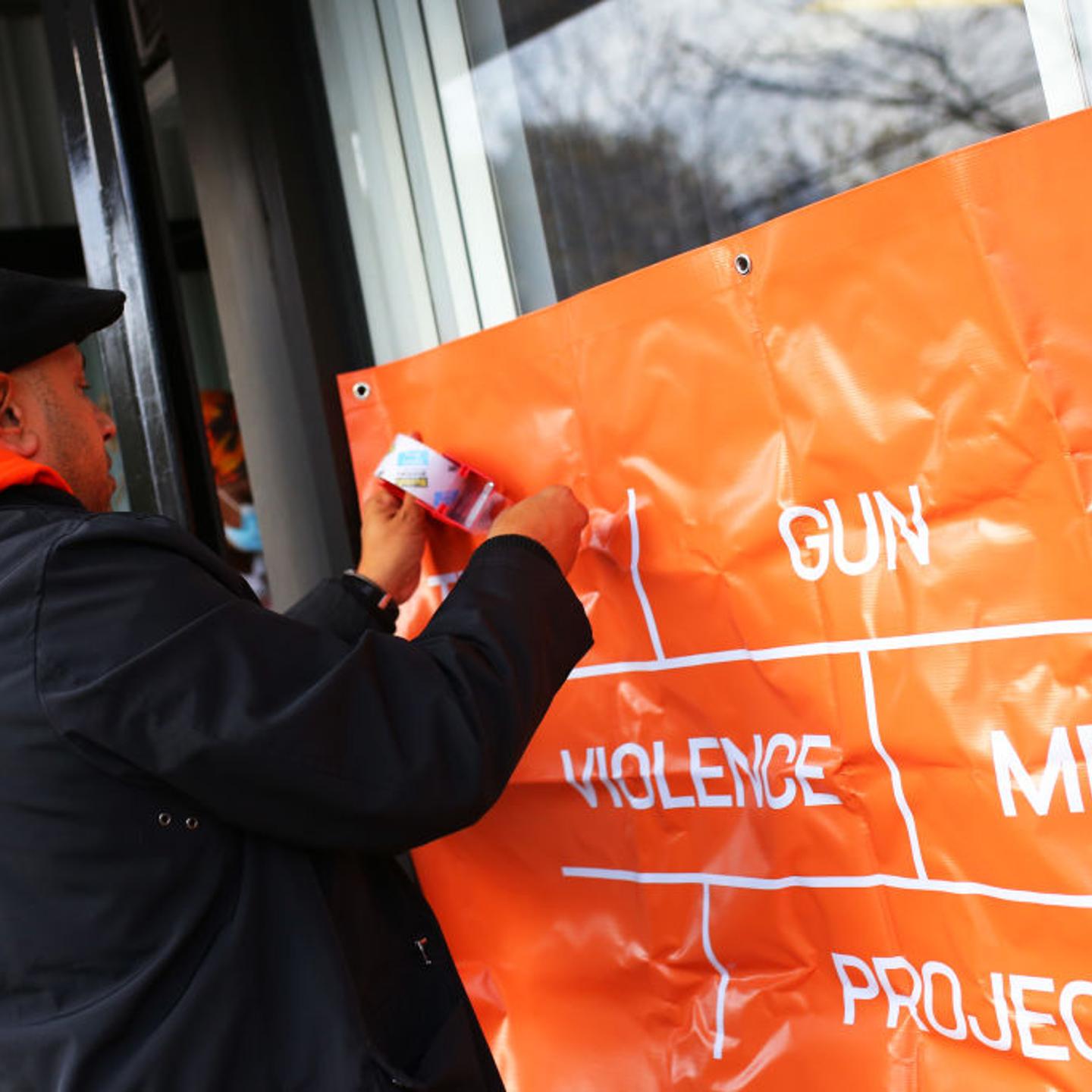 Jason Rodriguez, outreach supervisor with Lifecamp, hangs a banner as families of victims of gun violence gather at Where Do We Go From Here to drop of memorabilia for the Gun Violence Memorial Project on November 11, 2021 in Queens, NYC.