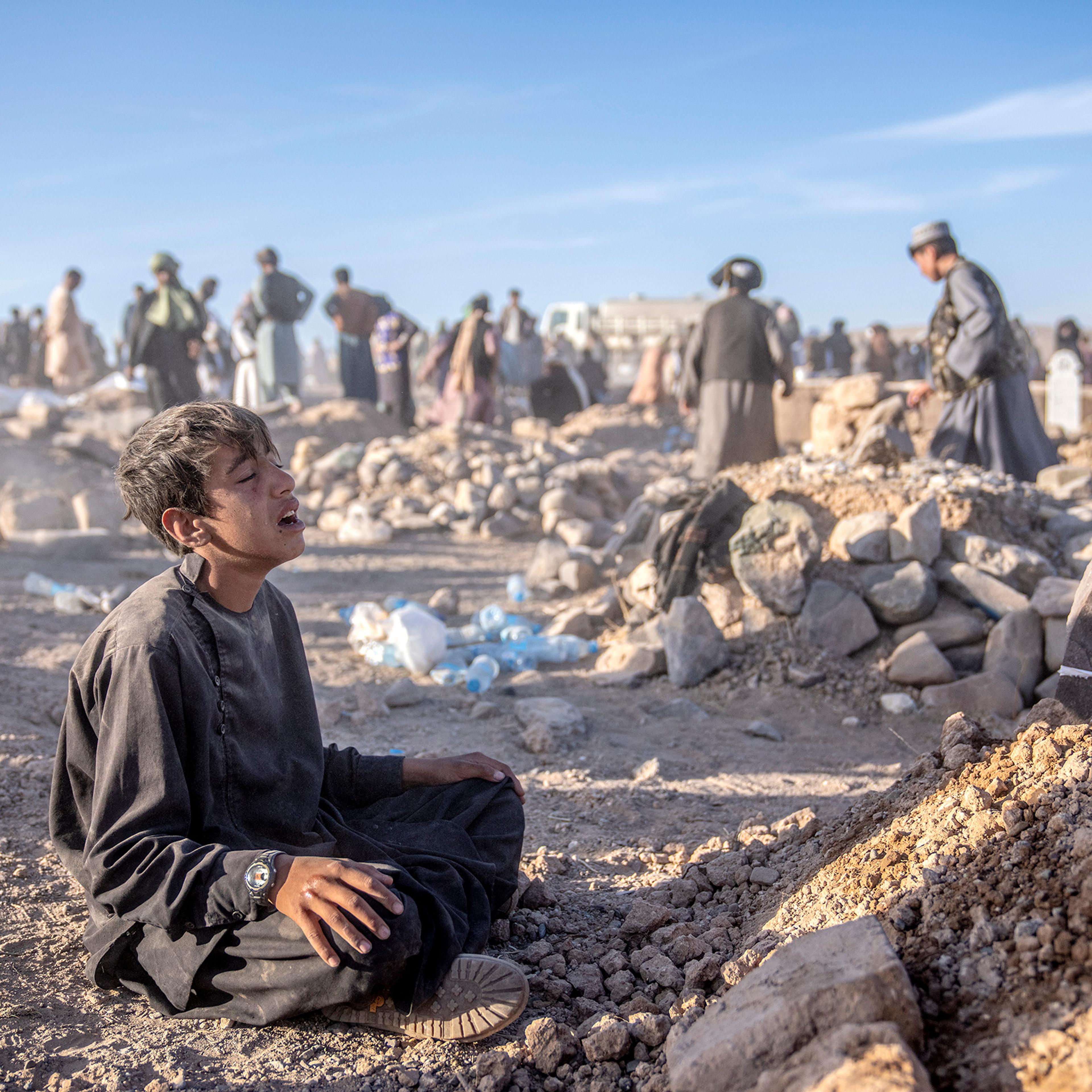 An Afghan boy mourns next to the grave of his little brother who died due to an earthquake, in Zenda Jan district in Herat province, Afghanistan, on Oct. 9.