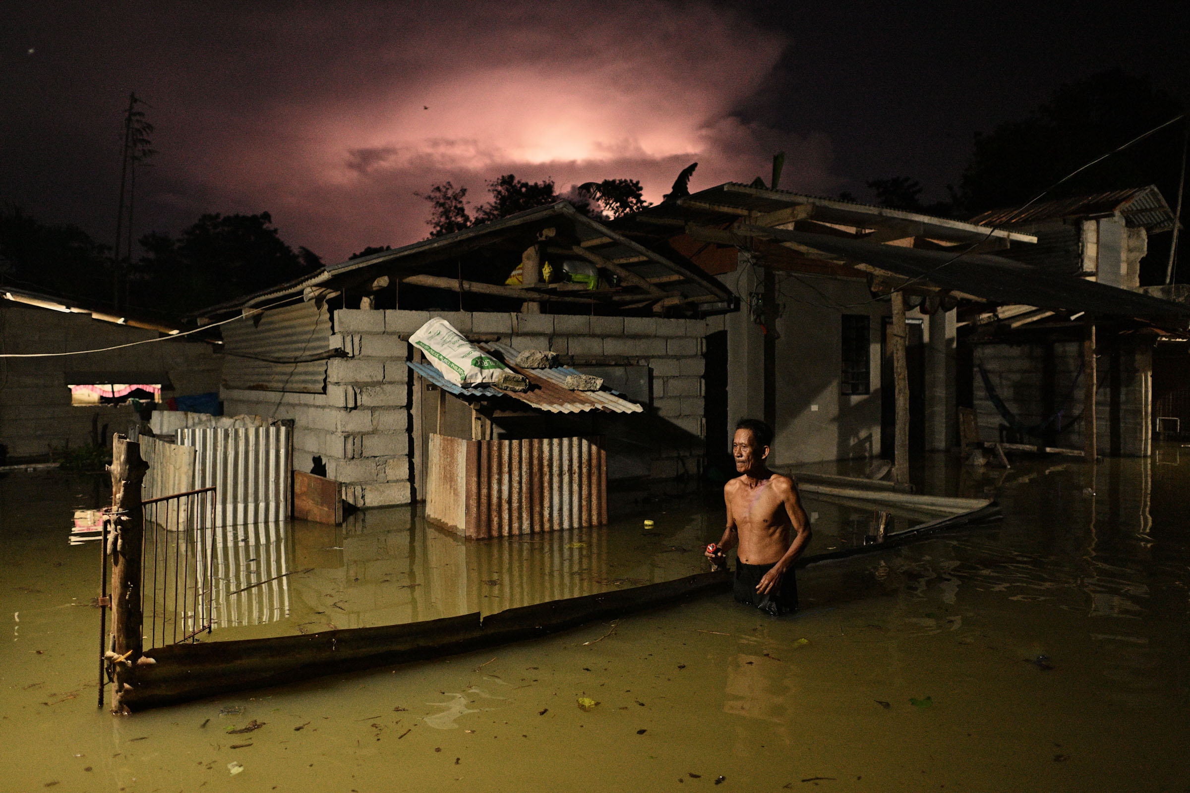 A resident wades through a flooded street caused by heavy rains from typhoon Toraji in Ilagan City, Isabela province, northern Philippines on Tuesday, Nov. 12