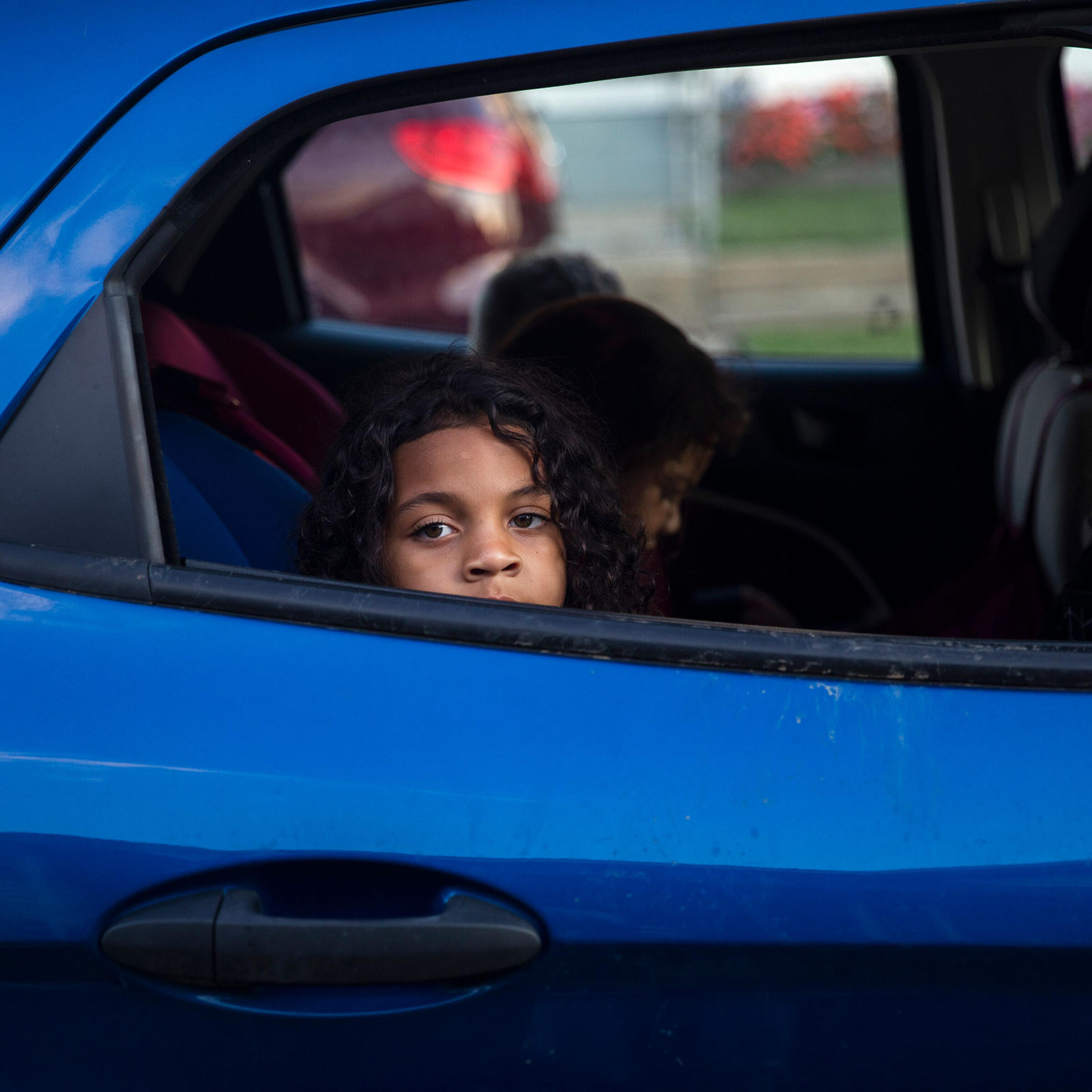 a young boy looks out the window of a blue car