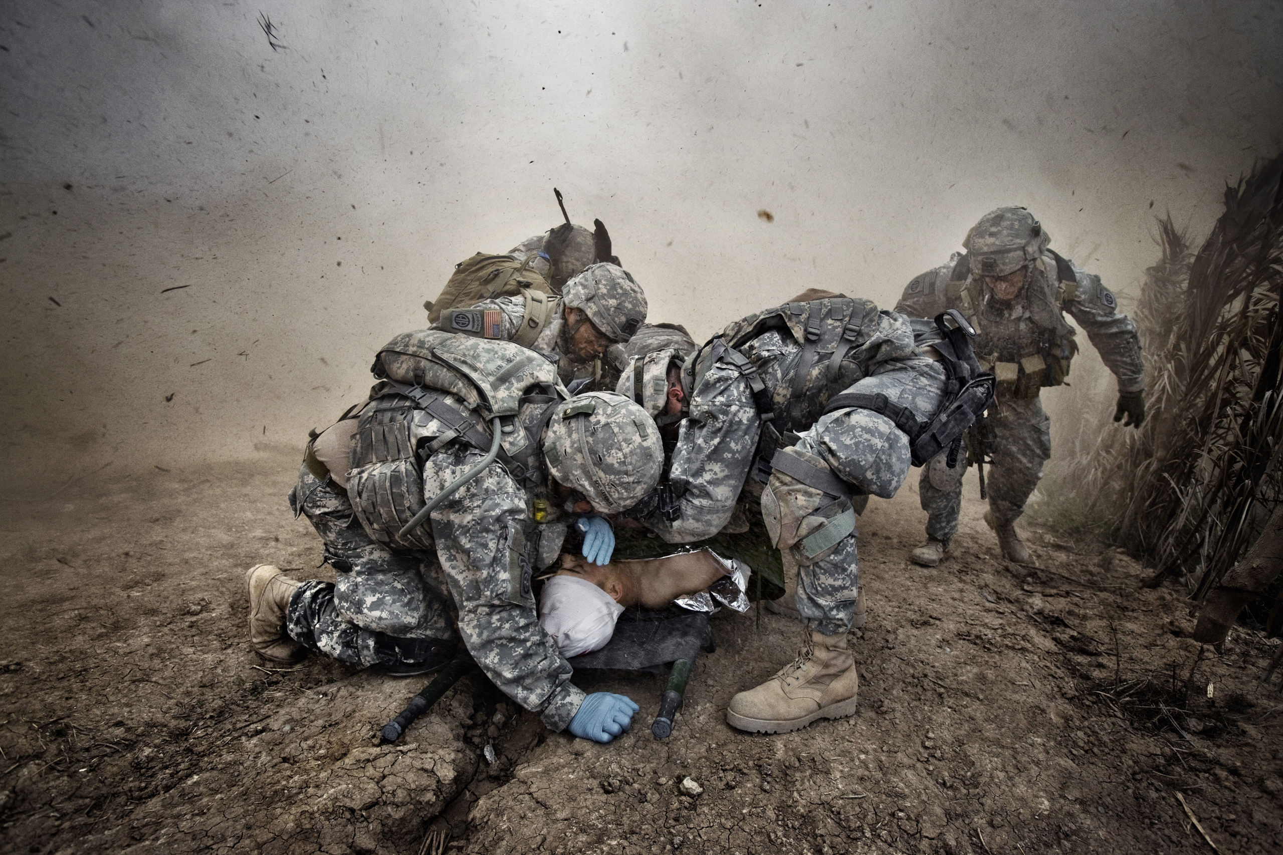 U.S. soldiers shield a wounded comrade from debris kicked up by a rescue helicopter descending on Qubah, Iraq, March 24, 2007. Fighting between U.S. forces and insurgents erupted in the village at dawn, when U.S. troops stormed the city and began house-t