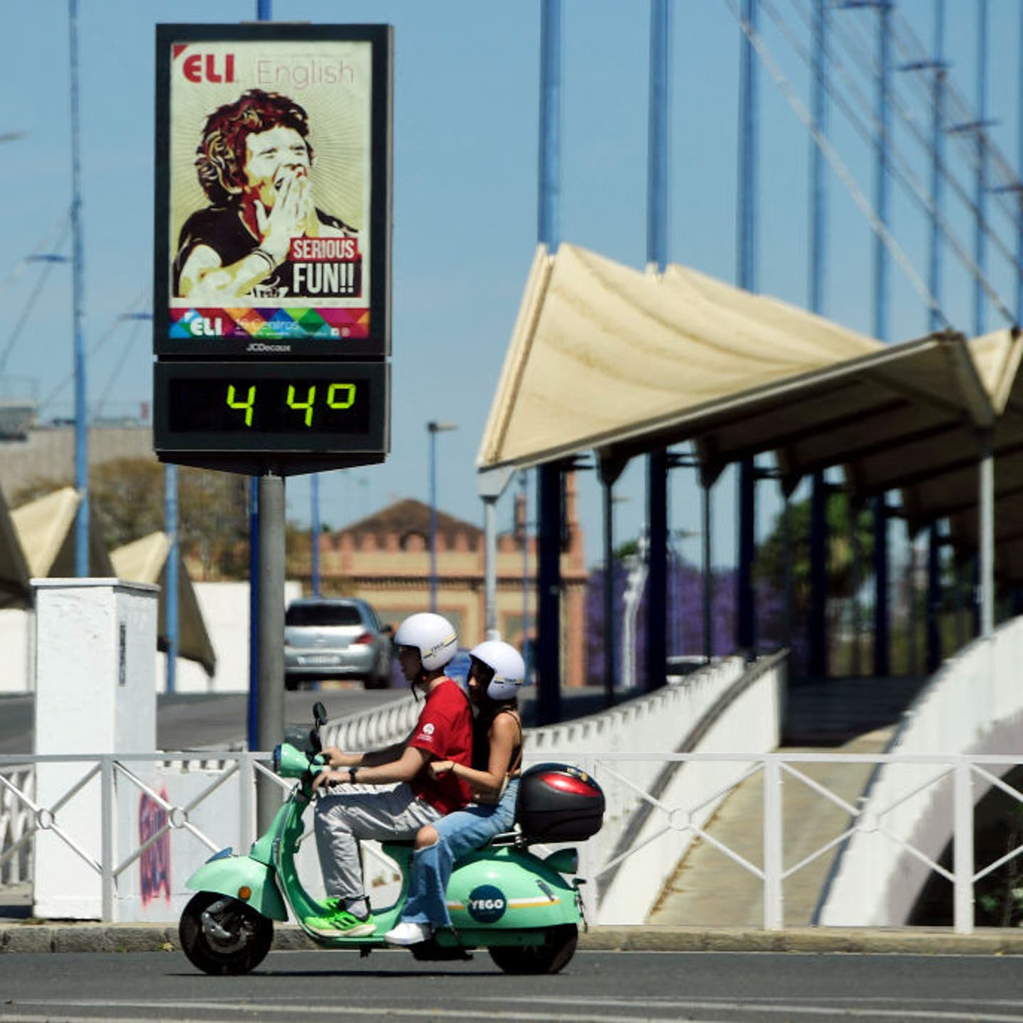 A couple ride a Vespa motorcycle past a street thermometer reading 44 degrees Celsius in Seville on April 26, 2023 as Spain is bracing for an early heat wave.