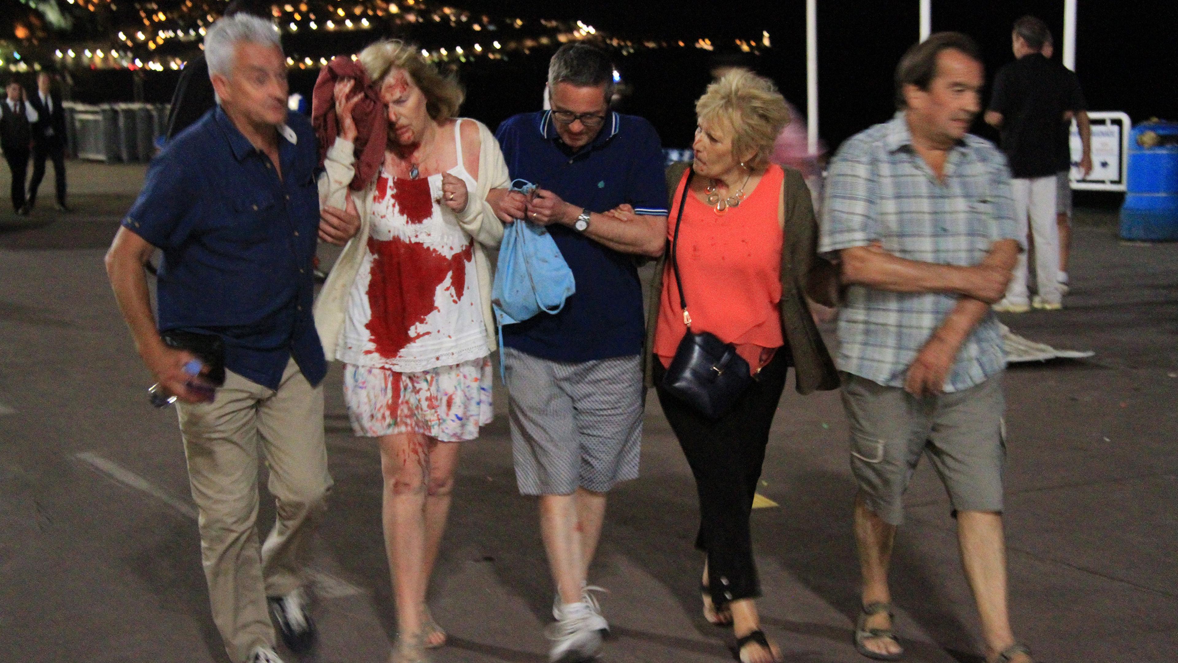 A woman whose shirt is covered in blood is helped after authorities said a truck slammed into a crowd in Nice, France, on July 14, 2016. French officials said more than 70 people were killed.