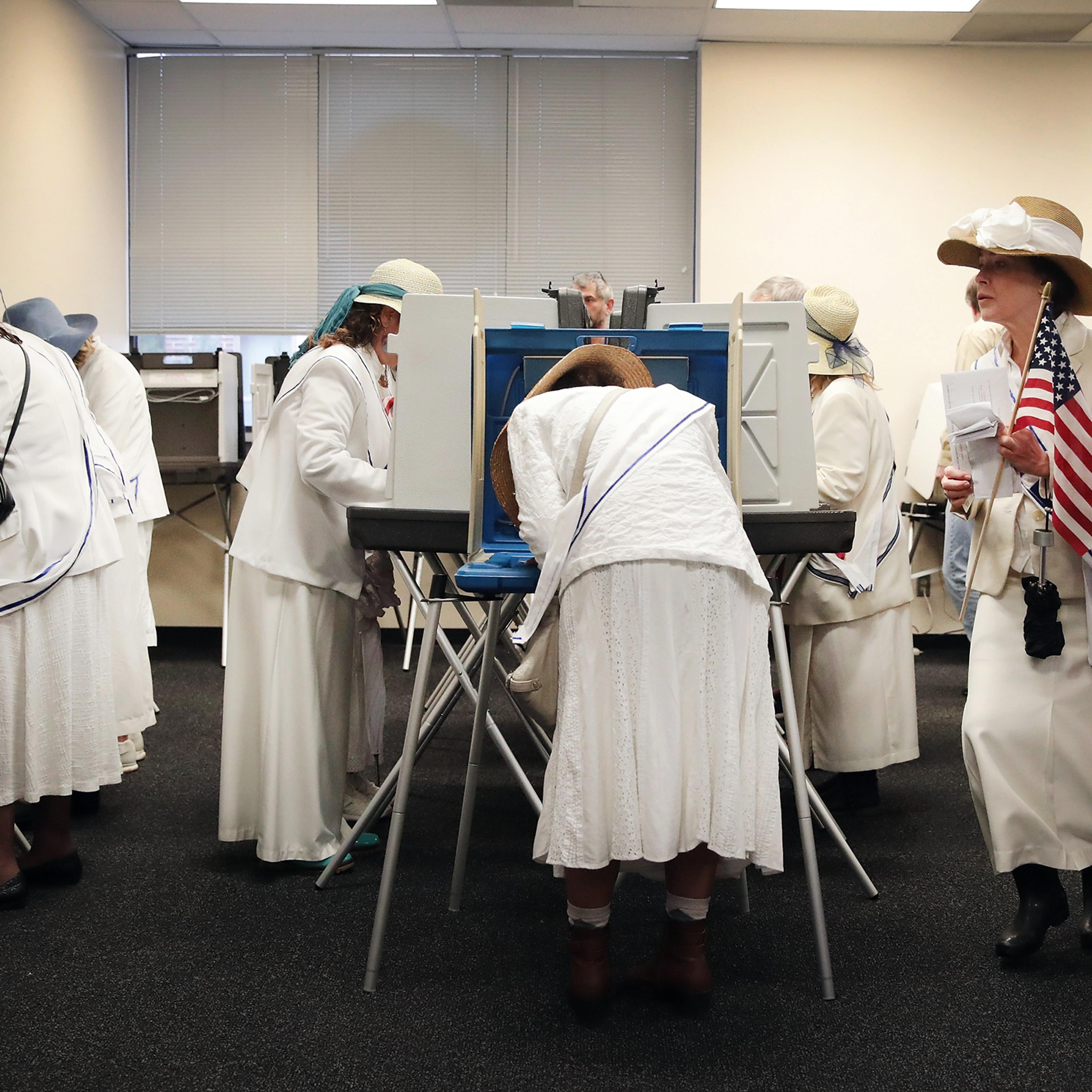 Women dressed as suffragettes cast ballots for the midterm elections at the Polk County Election Office on Oct. 8, 2018 in Des Moines.