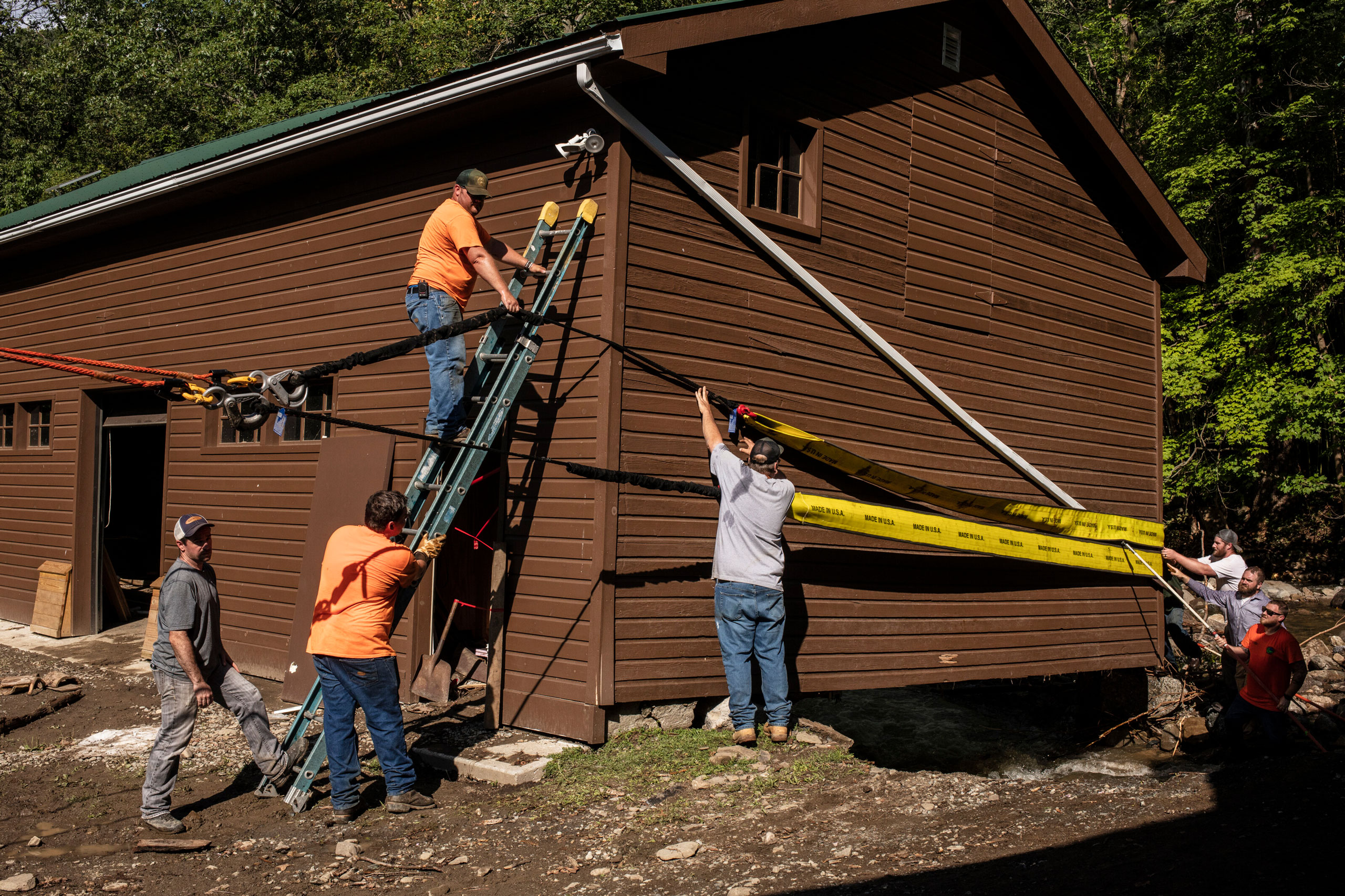 Workers prepare to move a building out of the creek after flash flooding