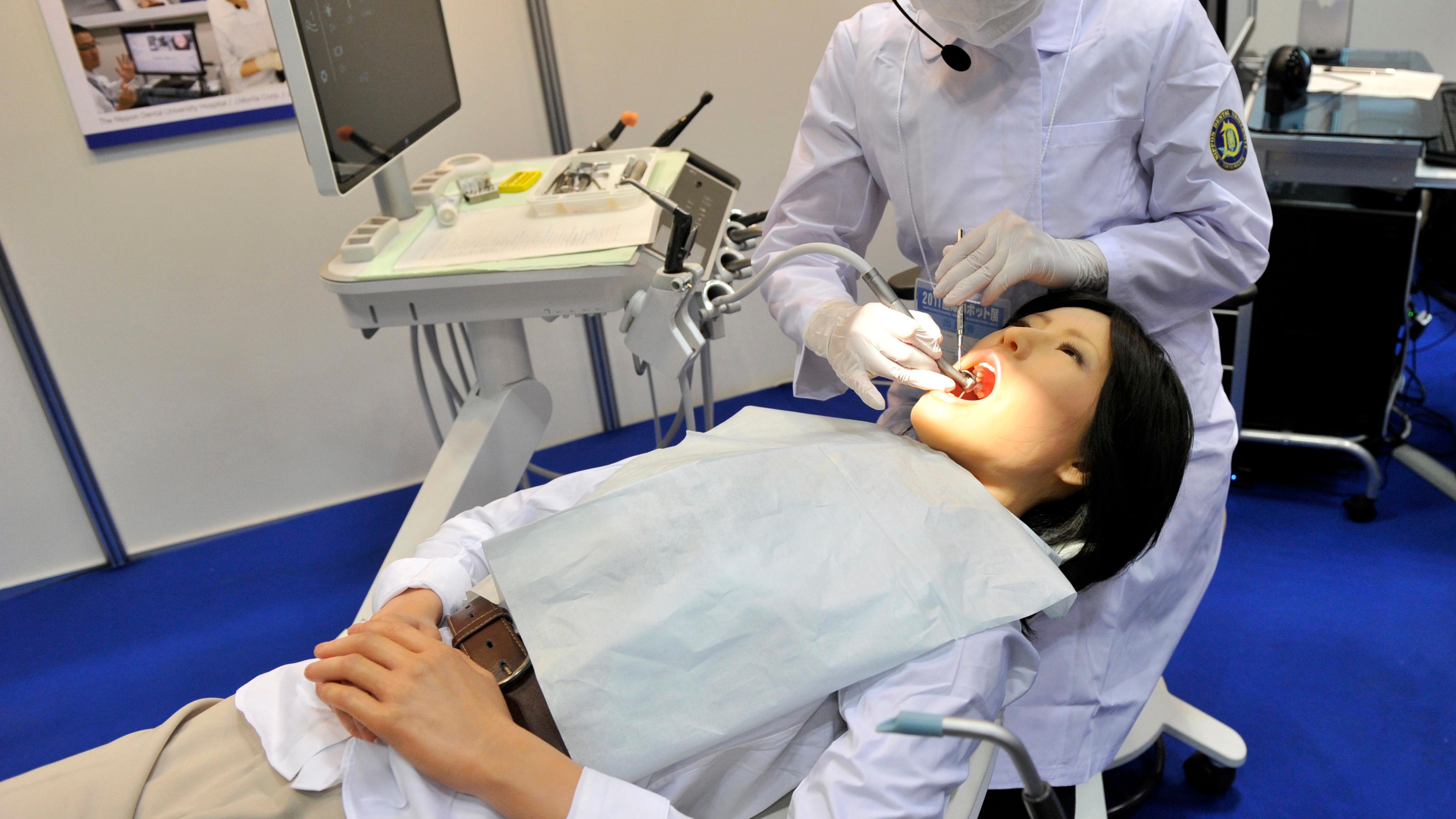 A Nippon Dental University Hospital staff member demonstrates a humanoid robot dental therapy simulator named "Simroid" at the International Robot Exhibition in Tokyo on November 9, 2011.