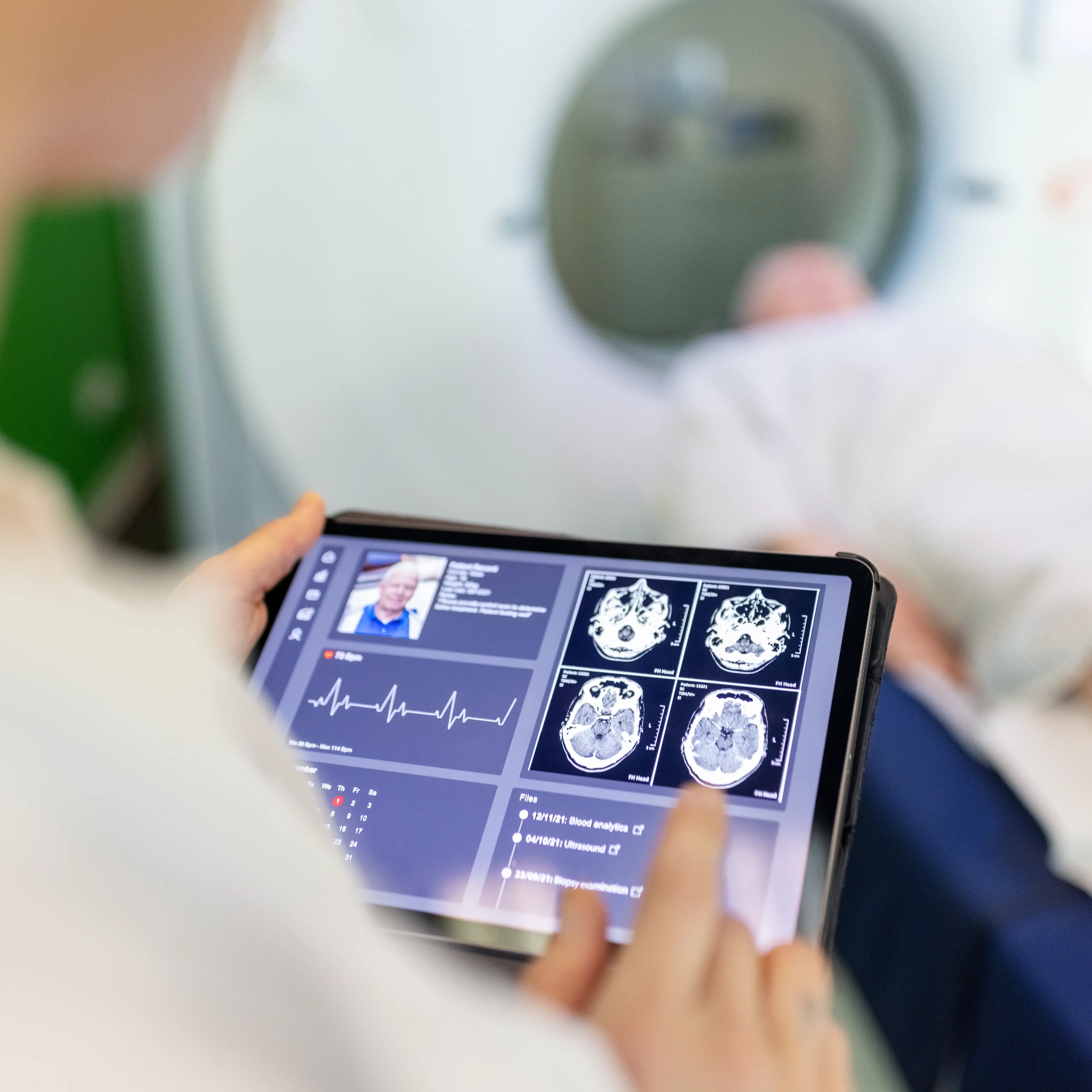 Neurologist examining patient's CAT scan images on digital table in clinic