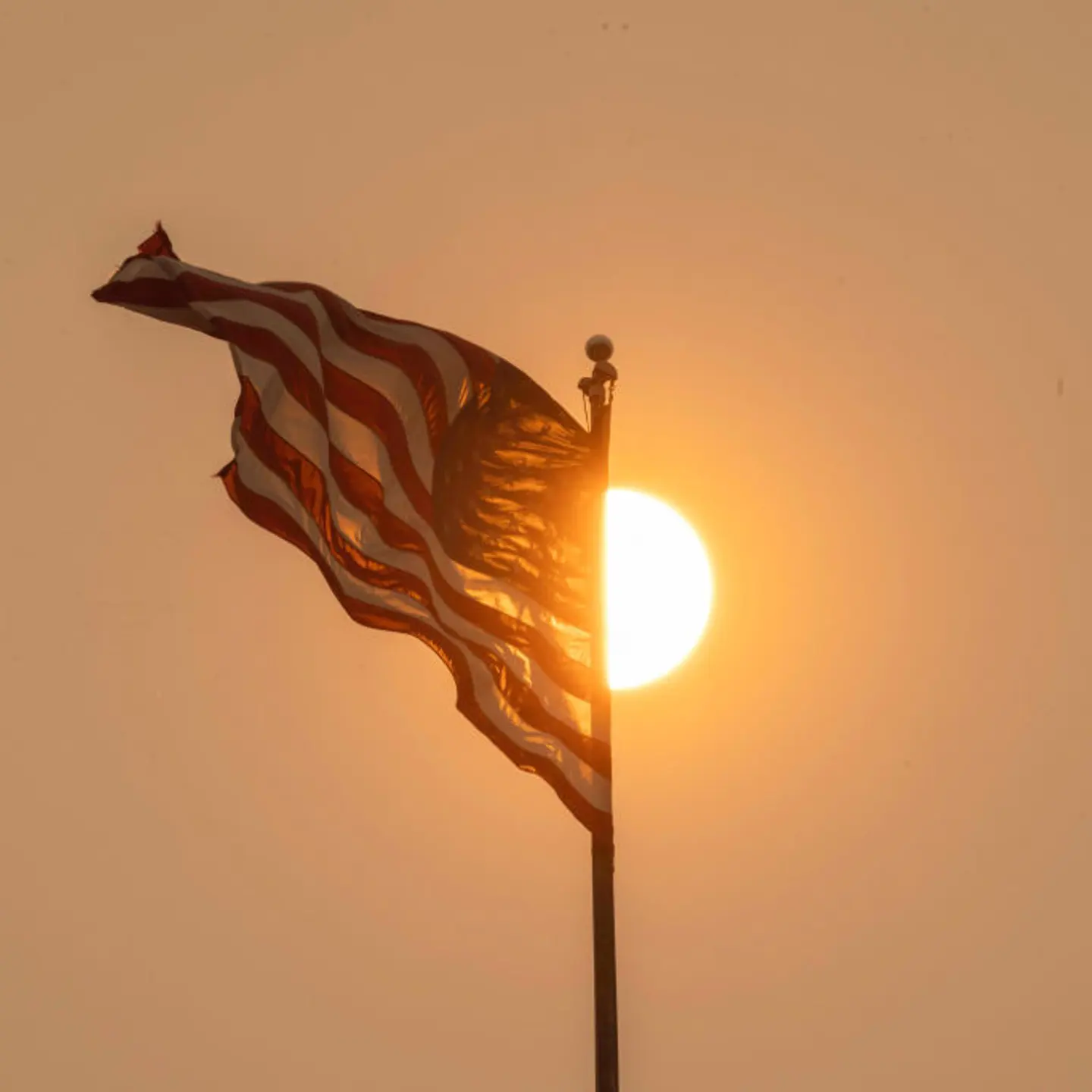 A hazy sun illuminates an American flag as smoke from wildfires blankets New York on June 7, 2023.