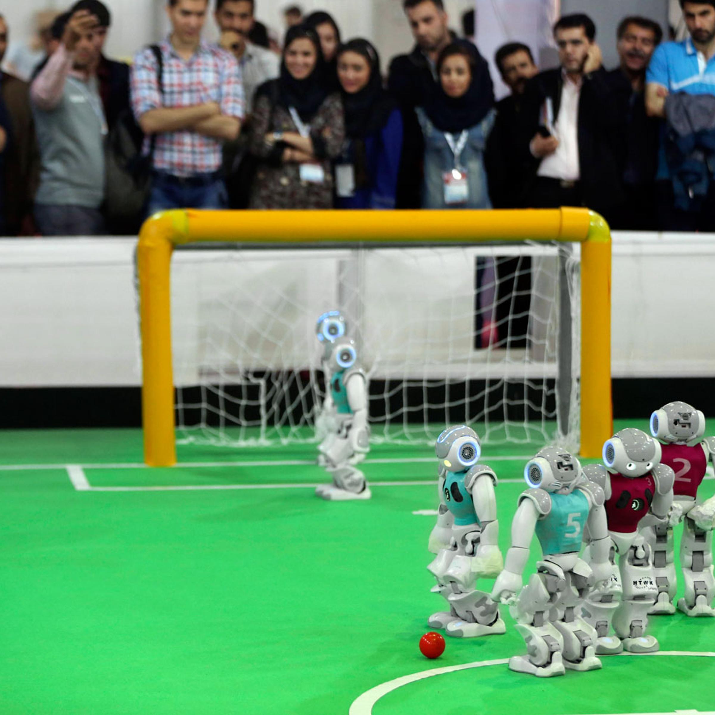 Humanoid robots play during a soccer match while visitors follow the competition in the international robotics competition, RoboCup Iran Open 2014, in Tehran, Iran on April 10, 2014.