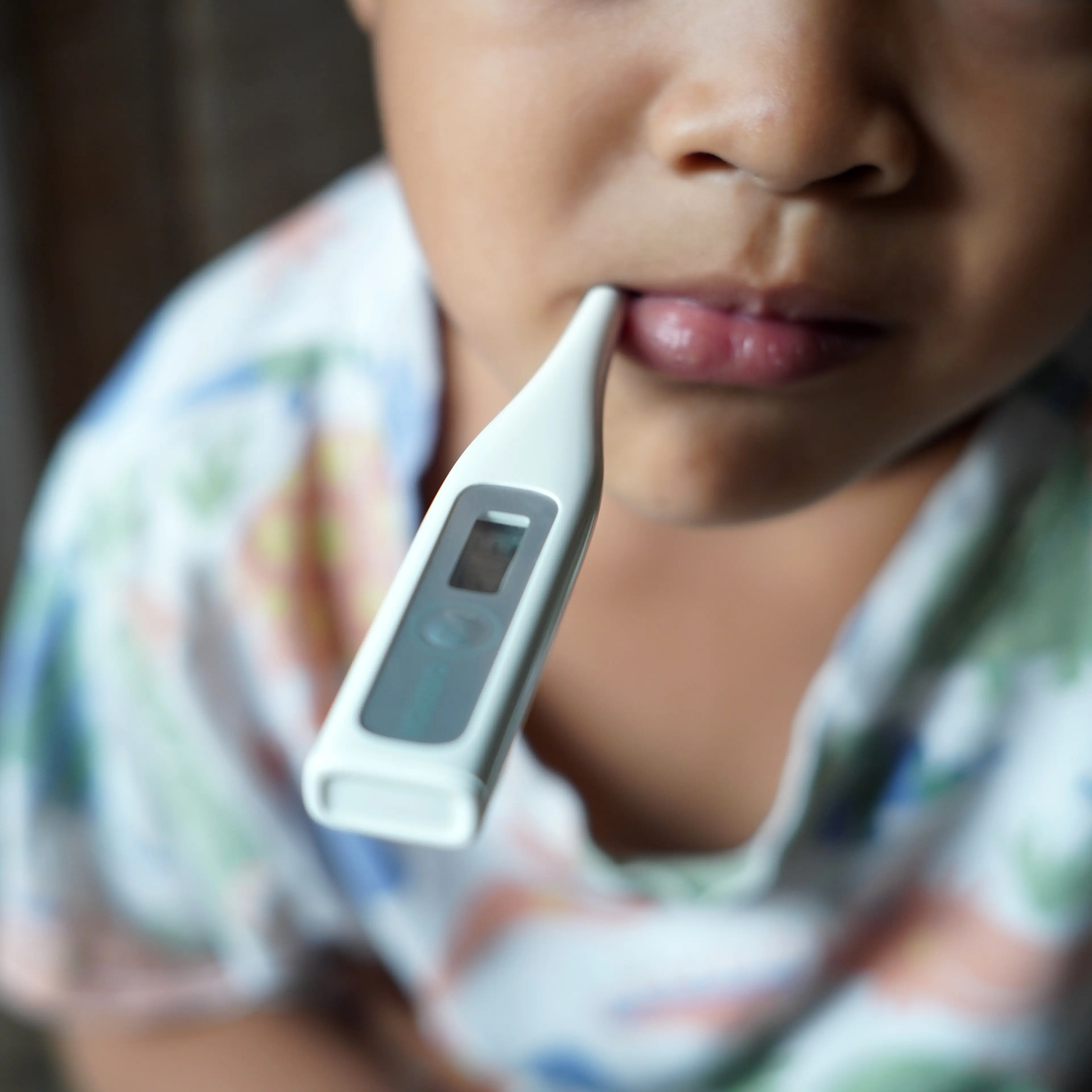 A sick child with a thermometer in his mouth