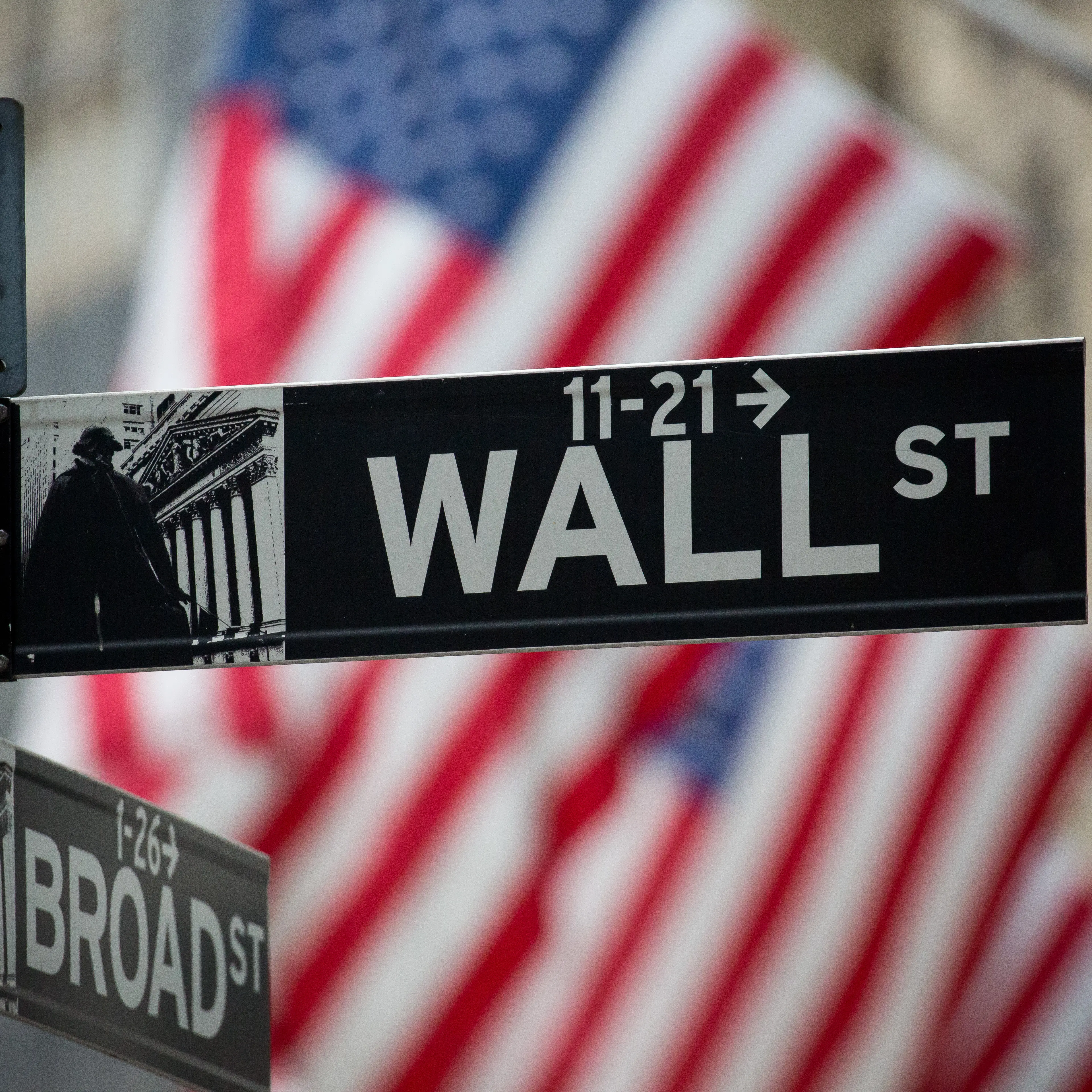 A Wall Street sign is displayed as American flags fly in front of the New York Stock Exchange (NYSE) in New York, U.S., on Monday, Nov. 21, 2016.