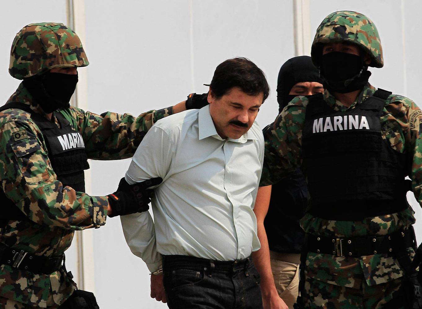 Joaquin "Shorty" Guzman is escorted by soldiers during a presentation at the Navy's airstrip in Mexico City Feb. 22, 2014.