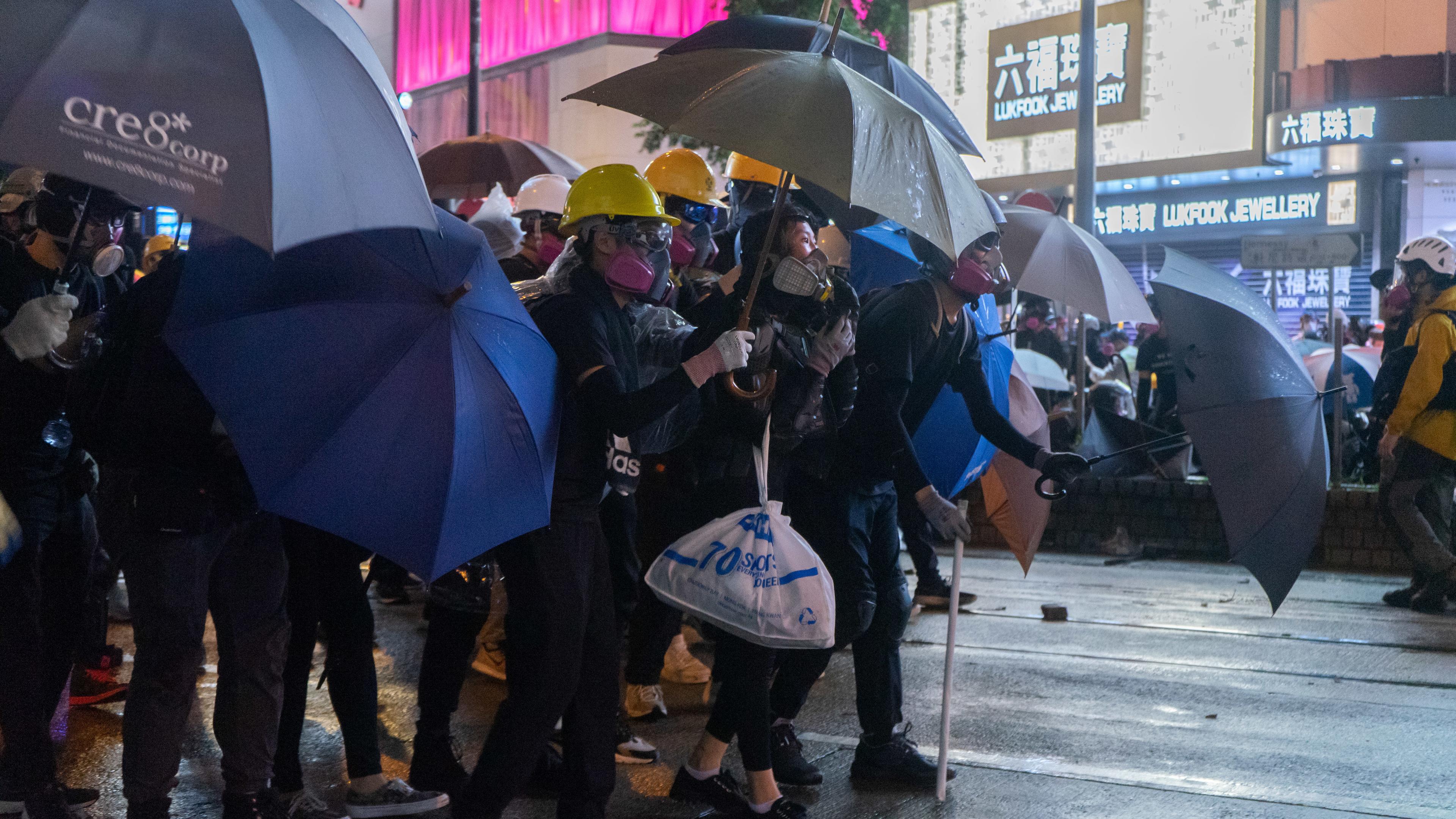 Protester hold umbrella to protect themselves from police