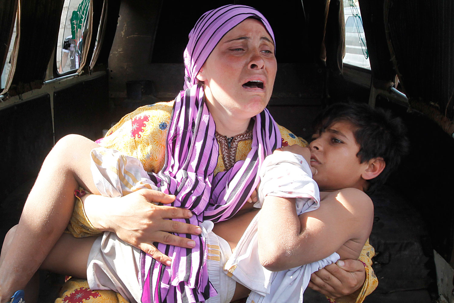 May 30, 2012. A Syrian woman cries as she carries her injured son, who was shot in his hand by the Syrian border guard when they were crossing a river from Syria to Lebanon, at the northern Lebanese-Syrian border town of Wadi Khaled, in Akkar, Lebanon.