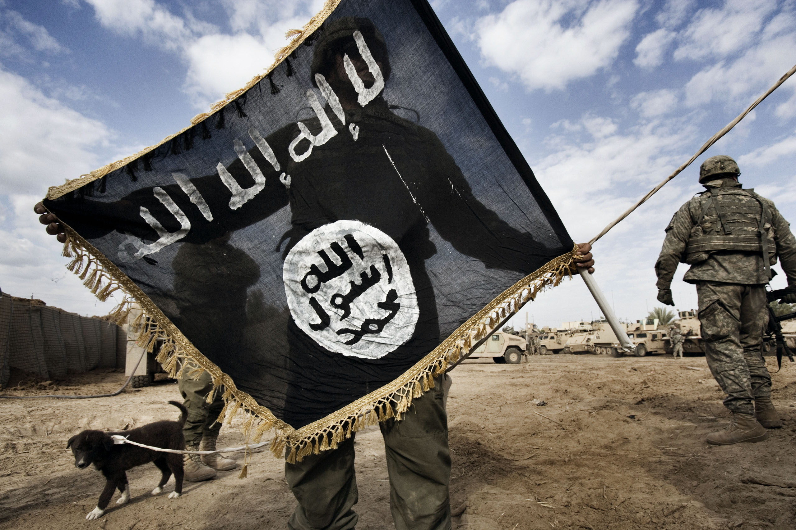 A U.S. soldier with 6th squadron, 9th cavalry of the 1st cavalry division holds the flag of al-Qaeda in Iraq (AQI) taken from the roof of a local school in Diyala province, northeast of Baghdad, which became a stronghold for the Sunni insurgency and AQI,