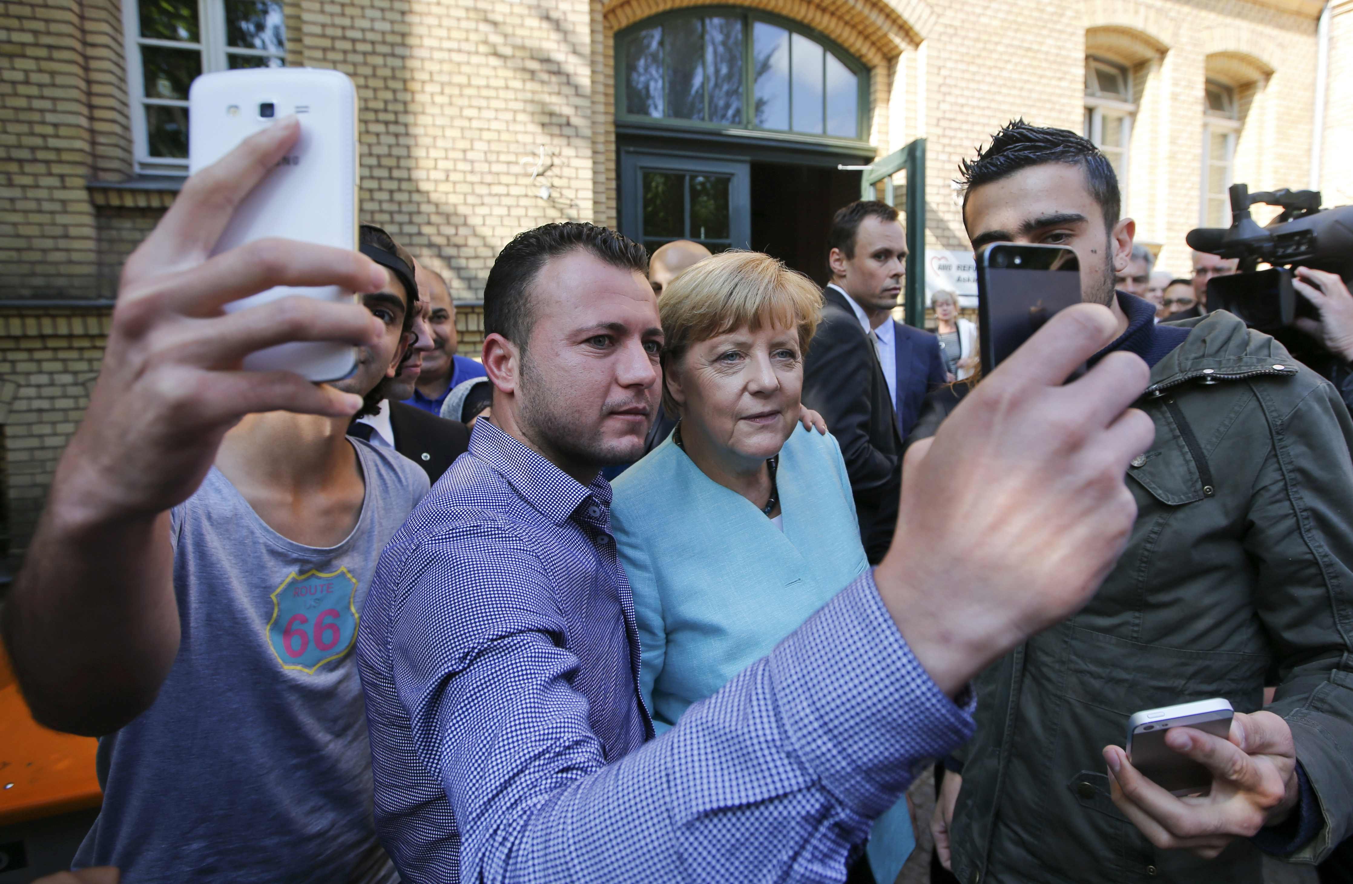 File photo of migrants taking selfies with German Chancellor Merkel outside a refugee camp in Berlin