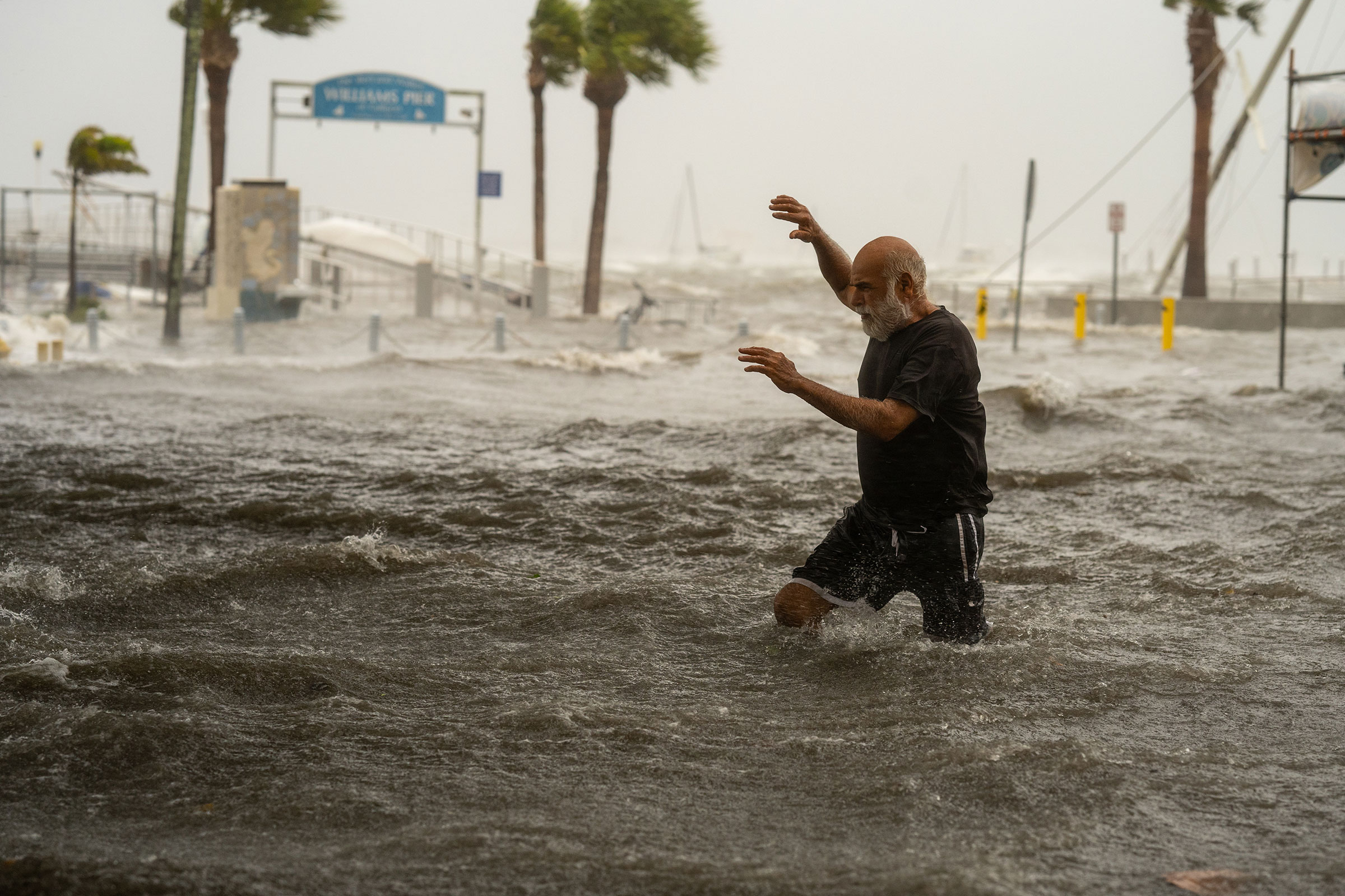 A man crosses a storm surge flooded area on the coast of Gulfport, Fla. on Sept. 26, 2024.