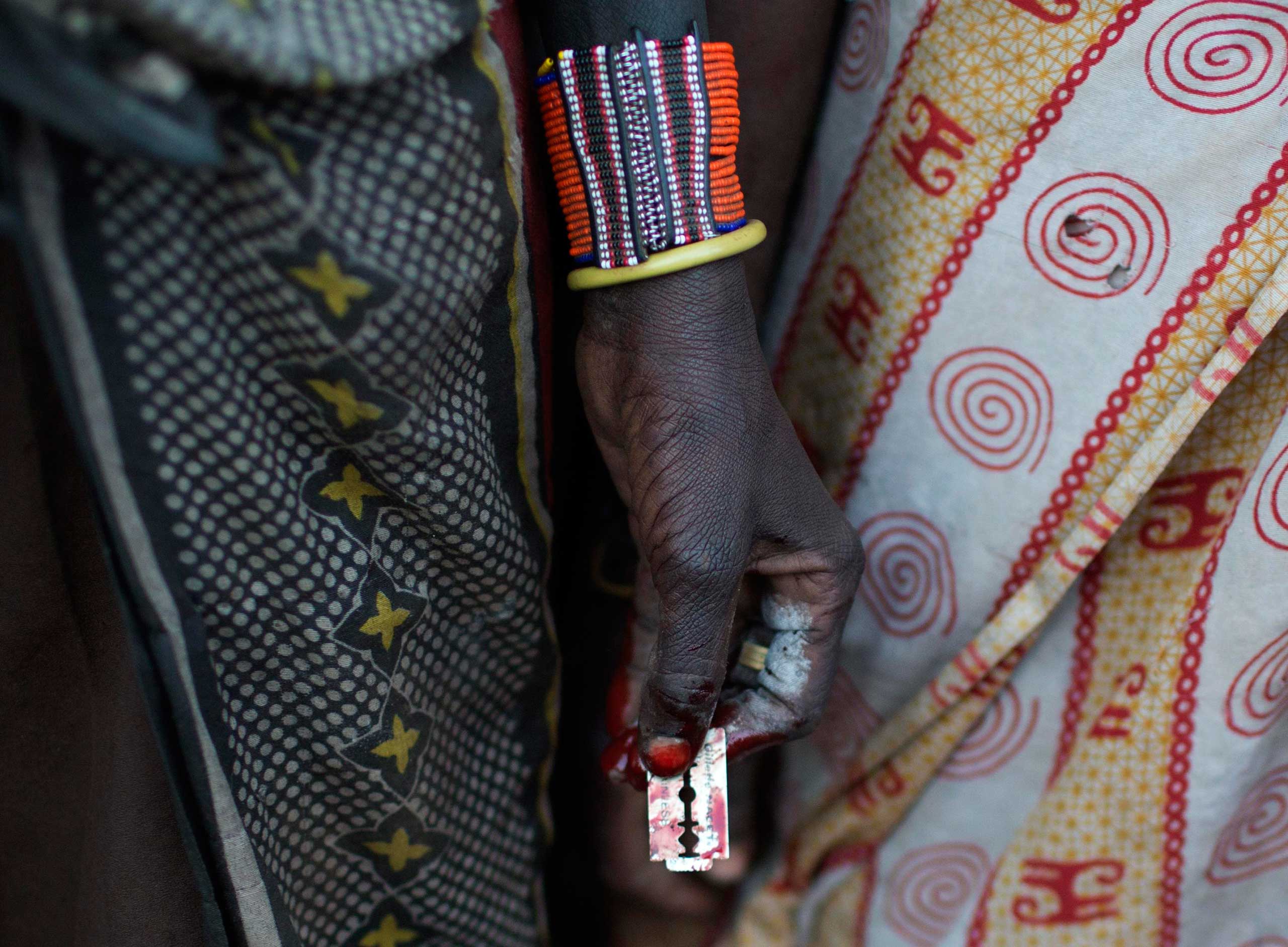 A Pokot woman holds a razor blade after performing a circumcision on four girls in a village about 80 kilometres from the town of Marigat in Baringo County, Kenya, Oct. 16, 2014.