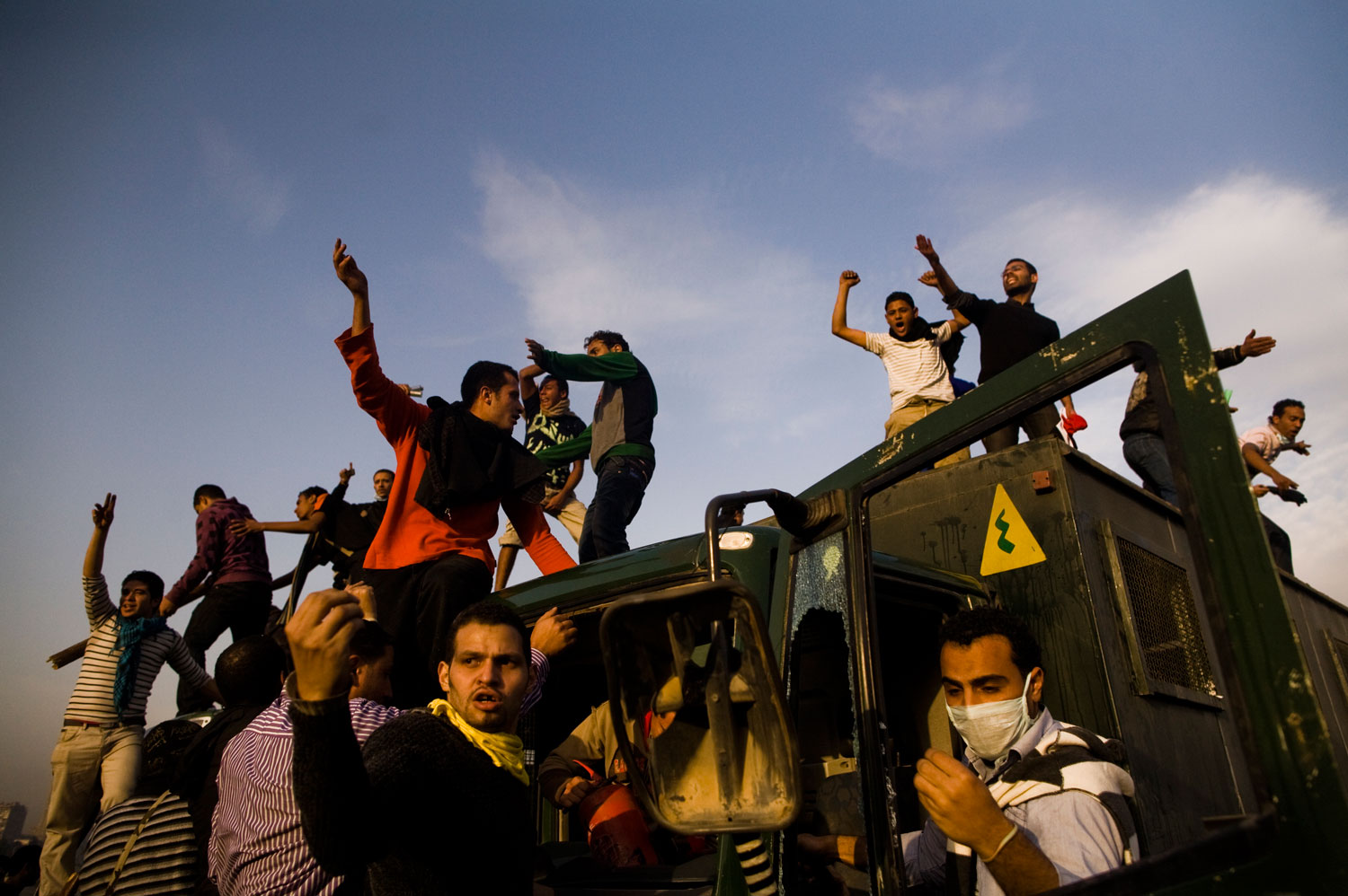 Protestors gather on a destroyed Egyptian police vehicle. 