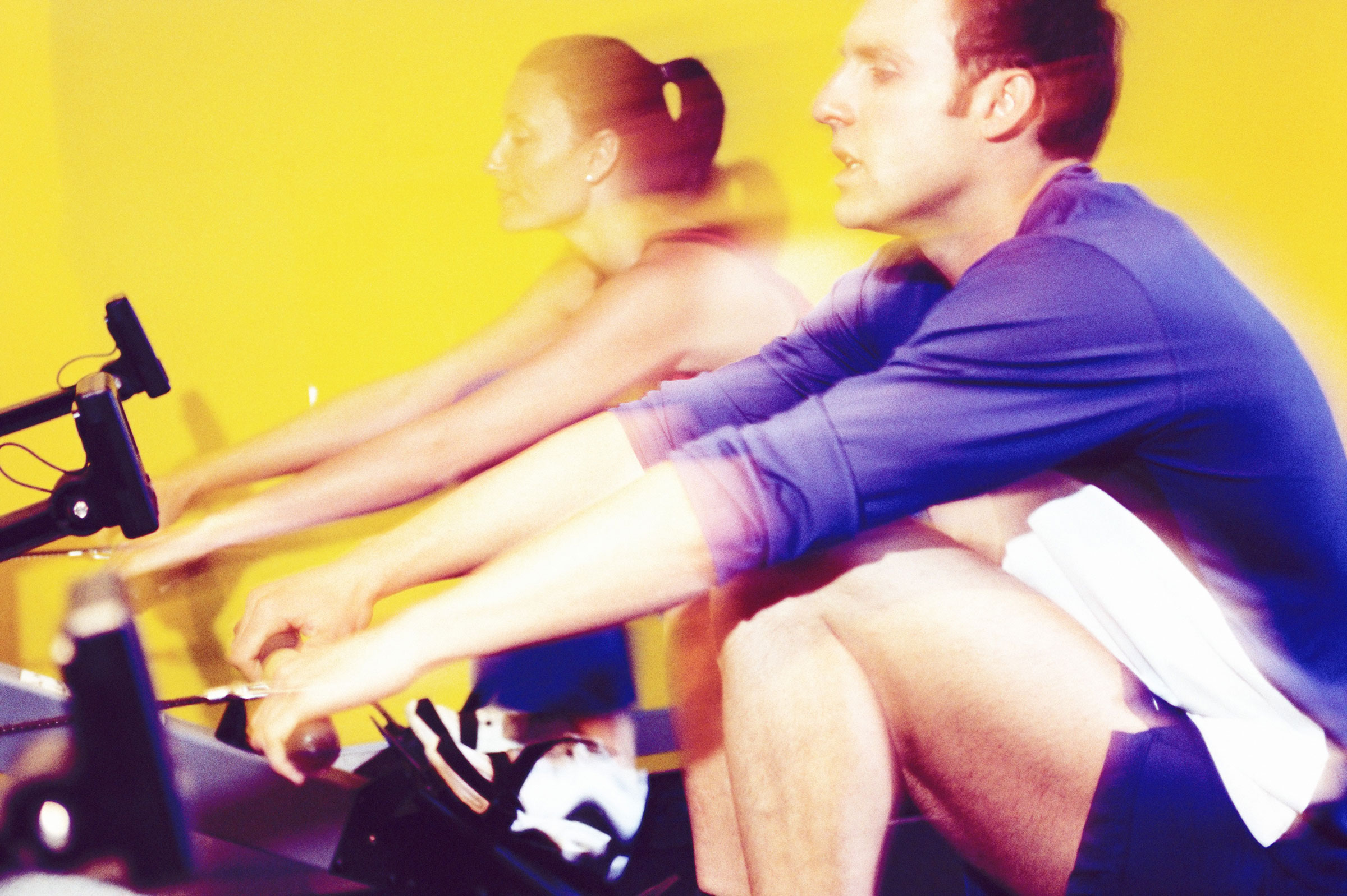 Two people using rowing machines at a gym