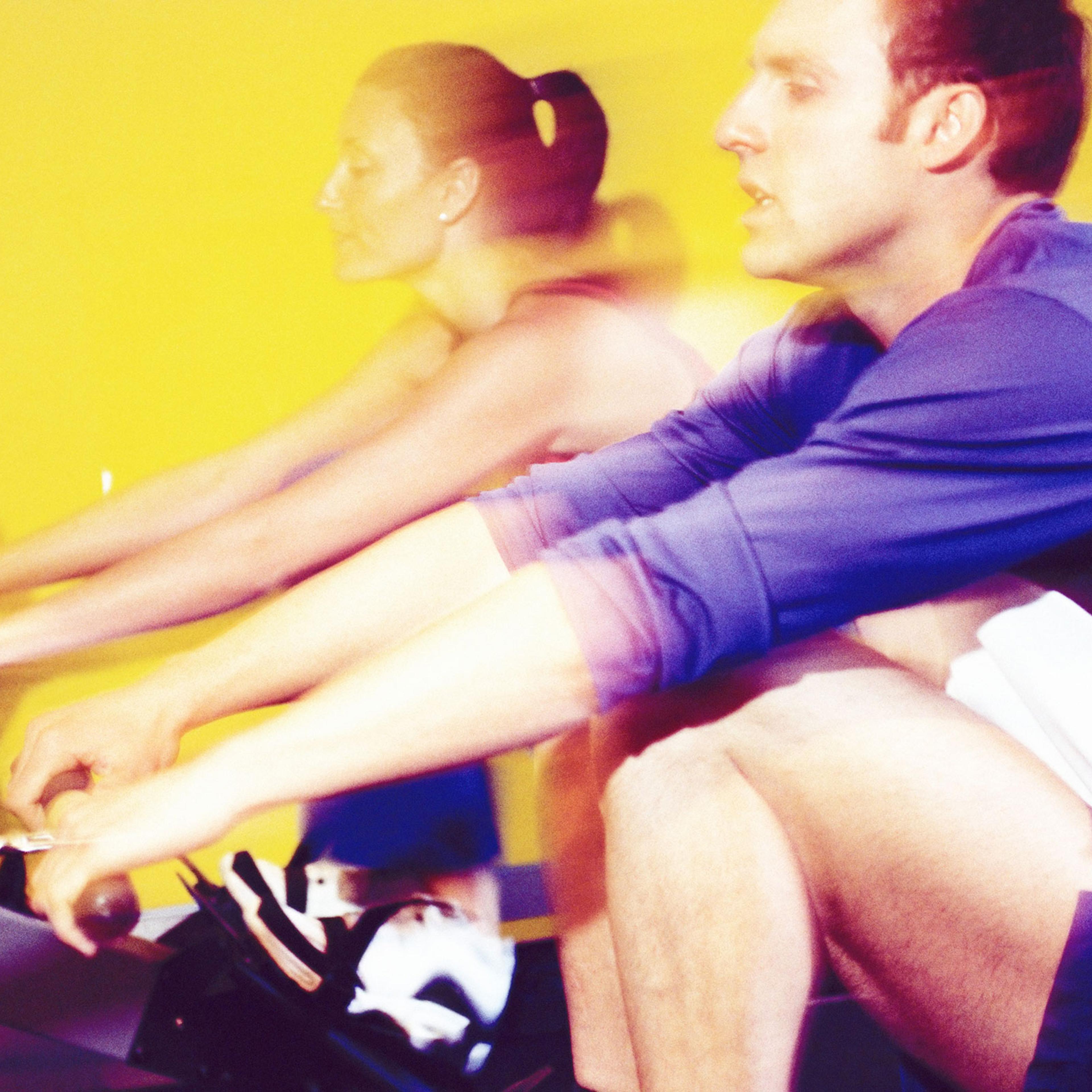 Two people using rowing machines at a gym