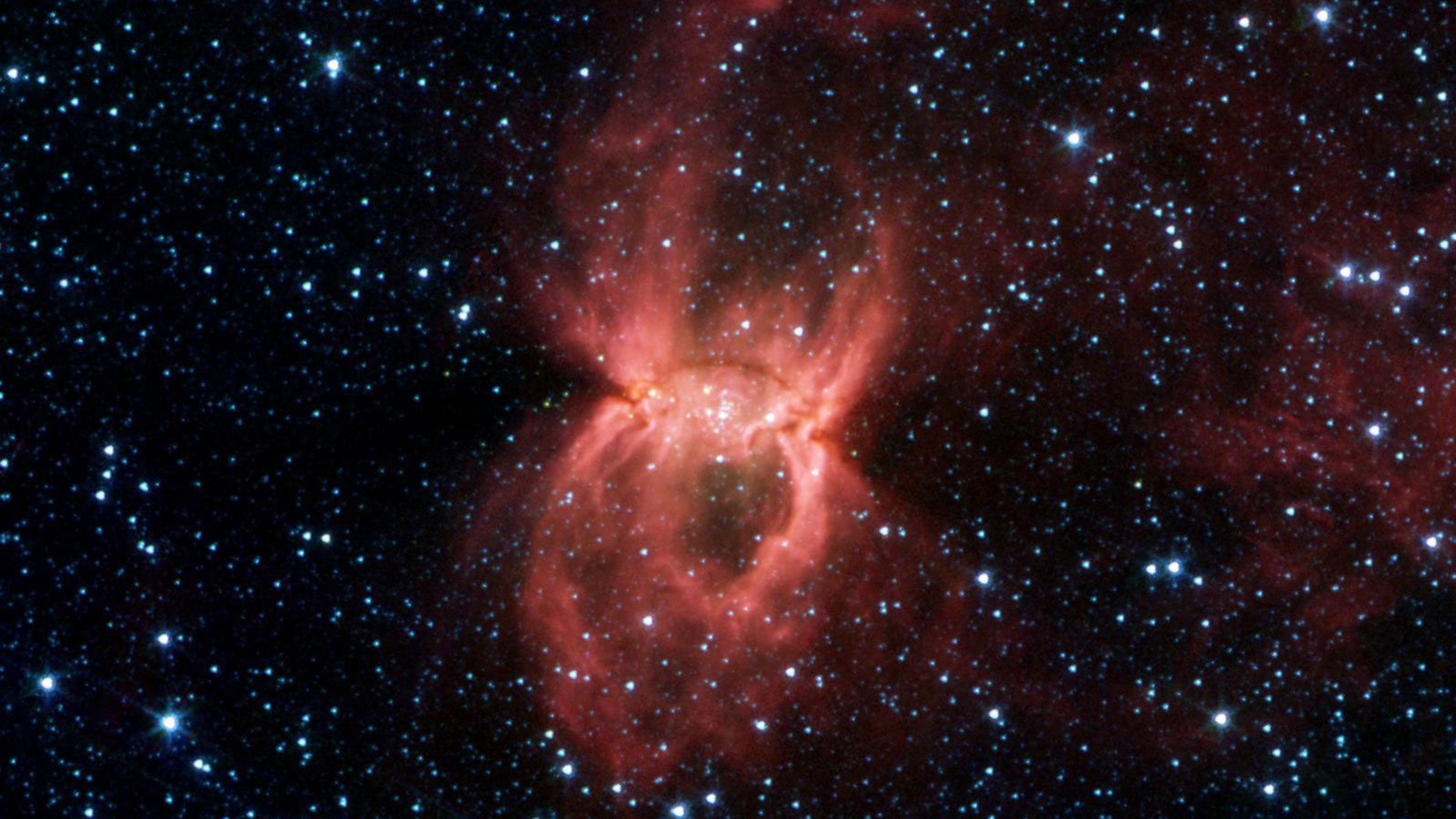 Black Widow Nebula Hides in the DustIn this Spitzer image, the two opposing bubbles are being formed in opposite directions by the powerful outflows from massive groups of forming stars. The baby stars can be seen as specks of yellow where the two bubble