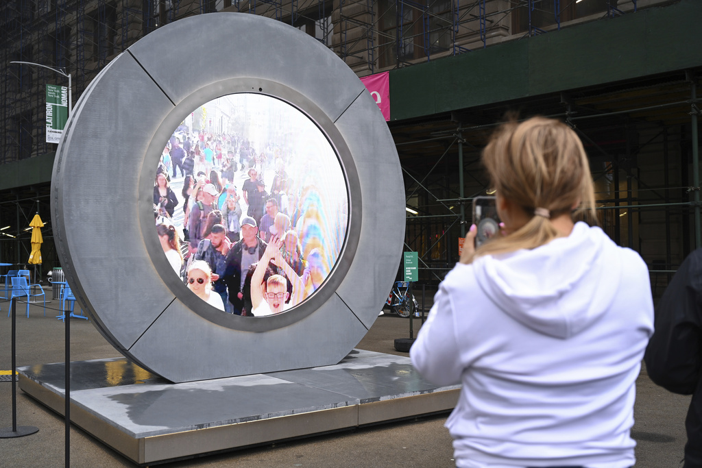 People interact with a livestream video "portal" in NYC