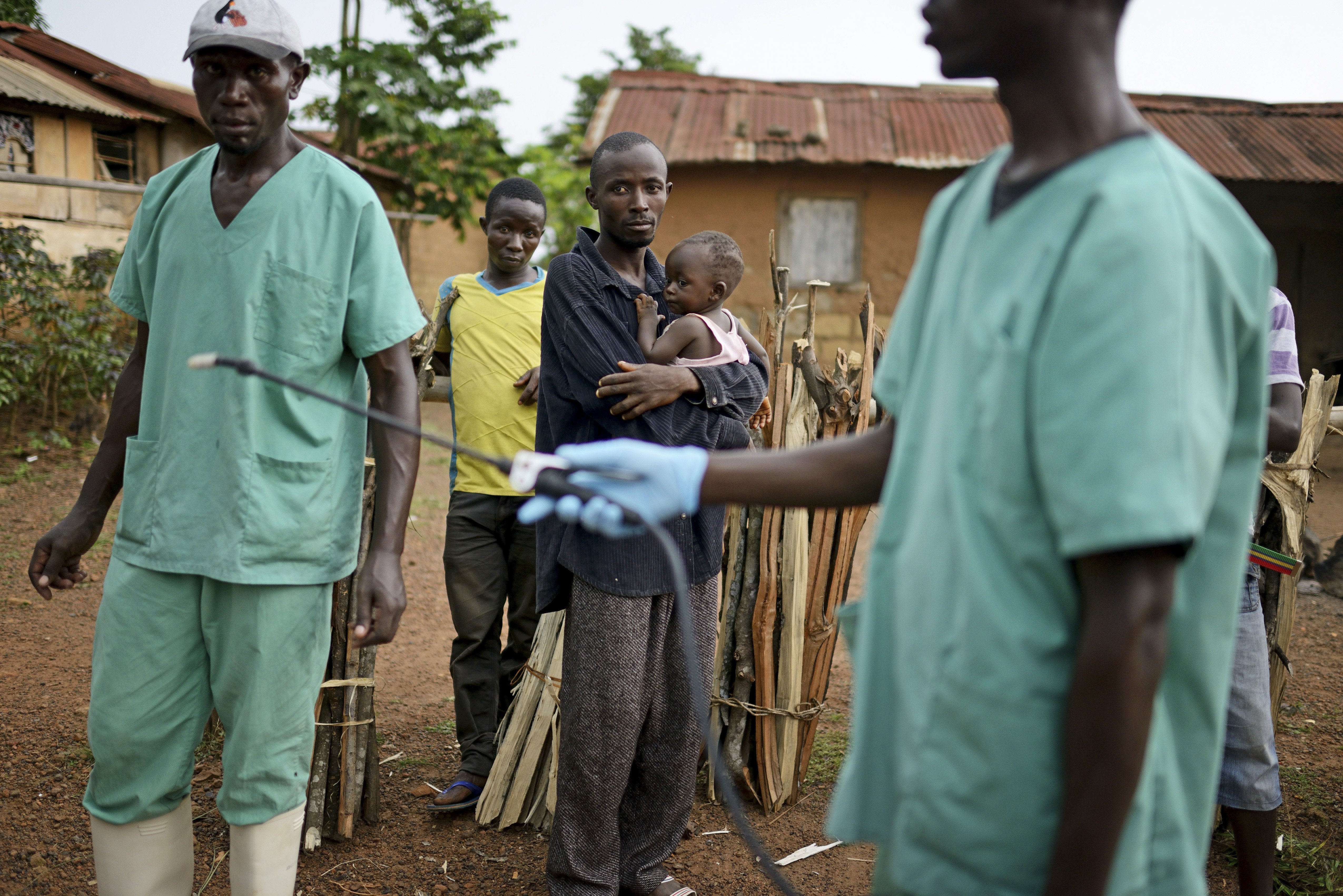 Locals watch workers with Doctors Without Borders as they disinfect after leaving a private clinic working to combat the spread of the Ebola virus in Teldou, Guinea, July 10, 2014.