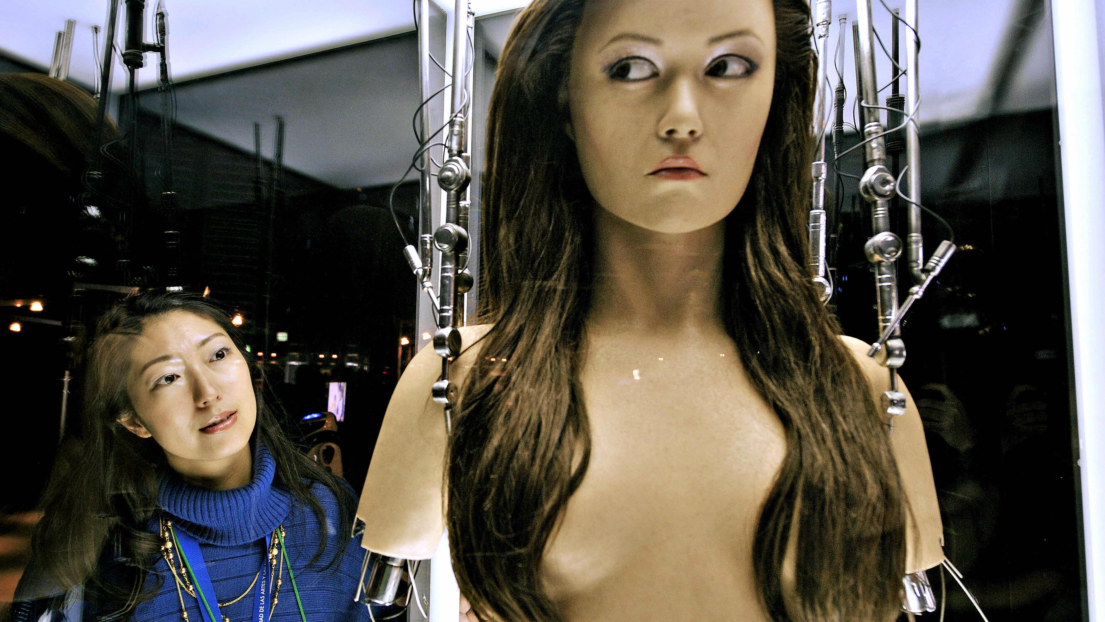 A woman watches a full-scale figure of a terminator robot "Cameron Phillipes" at a preview of the Terminator Exhibition in Tokyo on March 18, 2009.