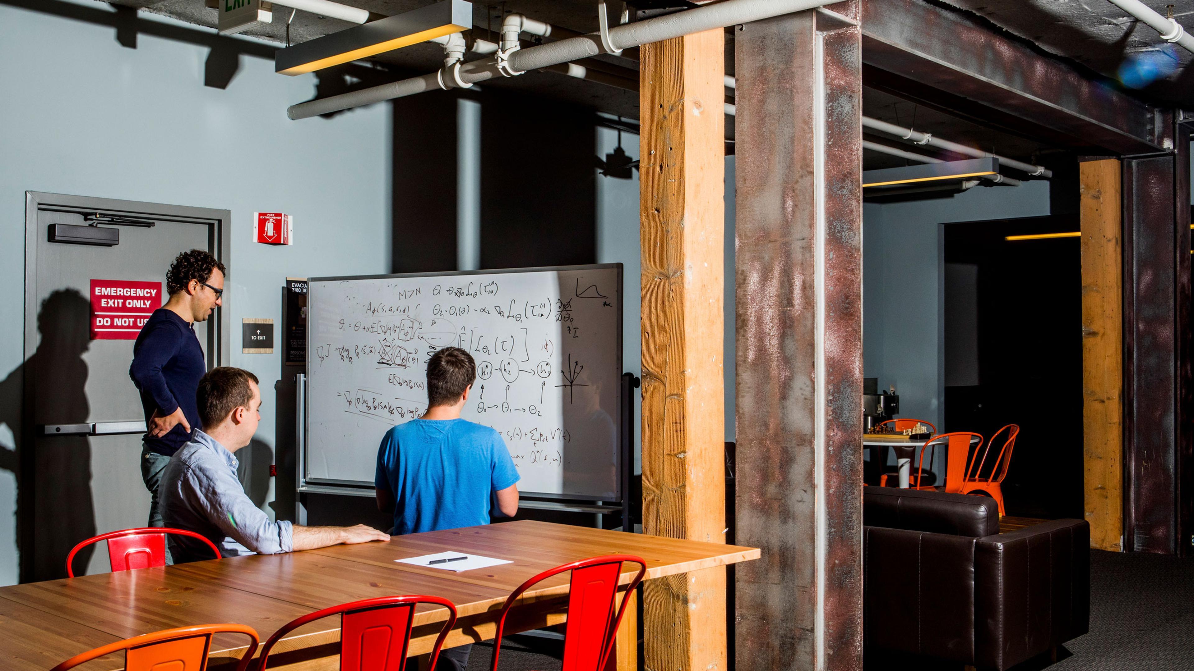From left: Paul Christiano, Dario Amodei, and Geoffrey Irving write equations on a whiteboard at OpenAI, the artificial intelligence lab founded by Elon Musk, in San Francisco, July 10, 2017.