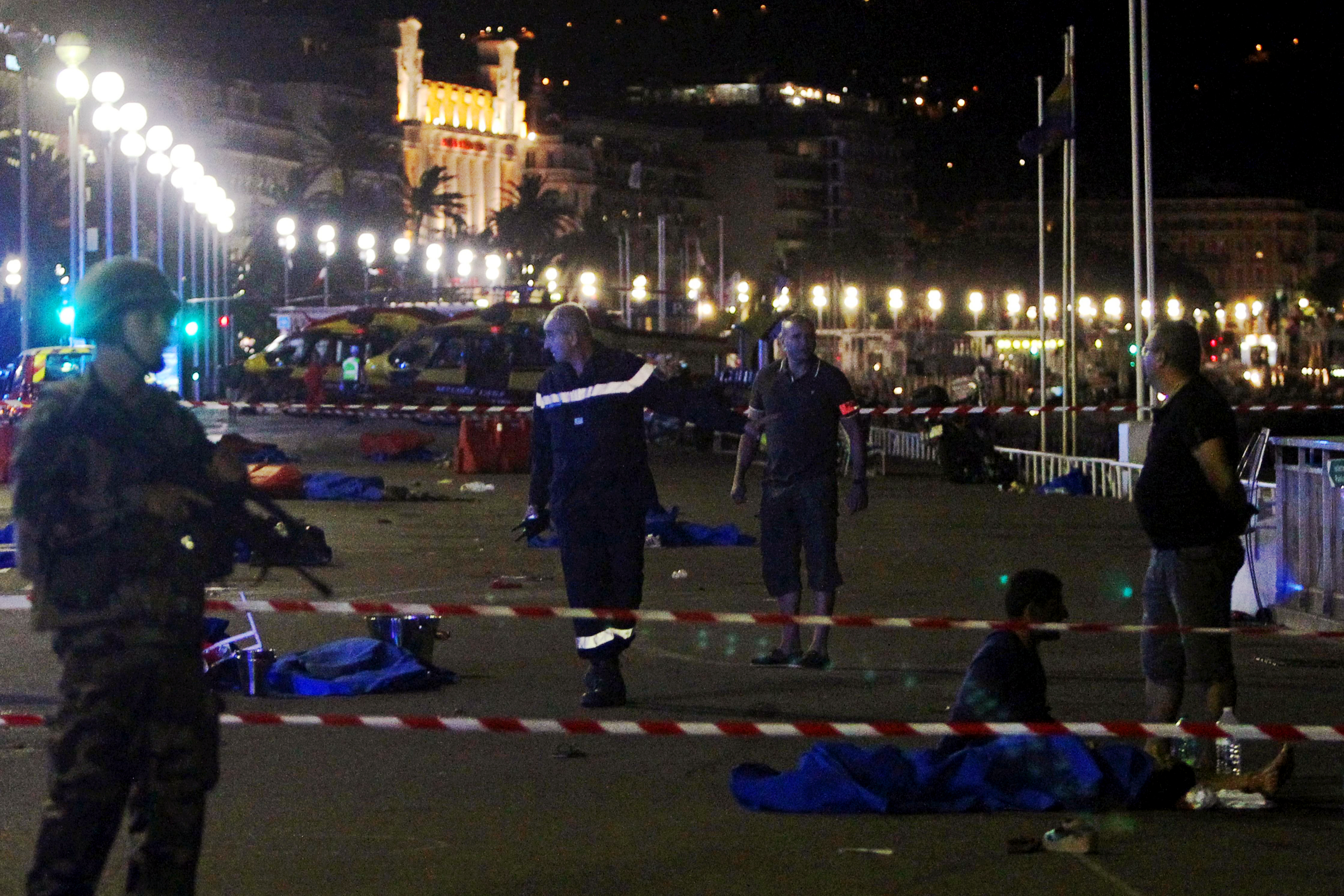 Soldiers, police officers and firefighters walk near bodies on the Promenade des Anglais seafront in the French Riviera town of Nice on July 15, 2016, after a van drove into a crowd watching a fireworks display.