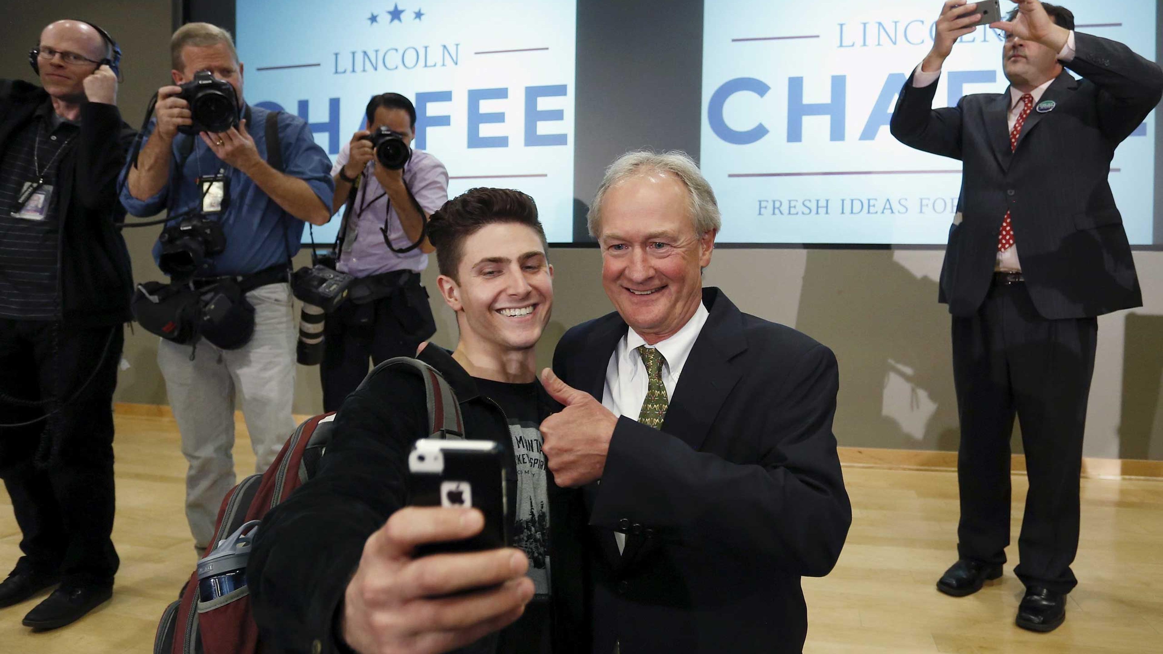 Former Rhode Island Governor Chafee poses for a selfie with a student after announcing he will seek the Democratic nomination to be U.S. president during an address to the GMU School of Policy, Government, and International Affairs in Arlington