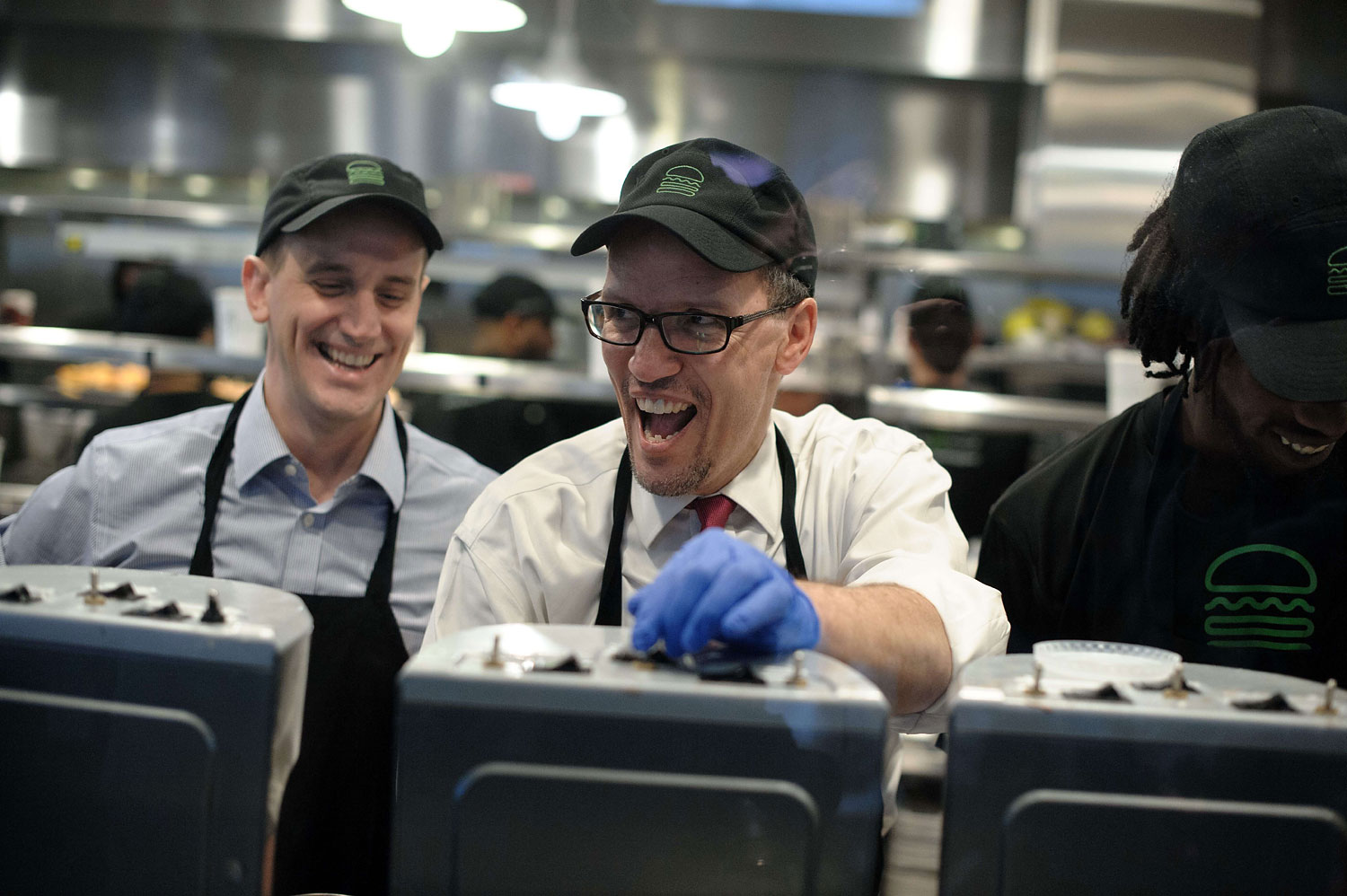 Labor Secretary Thomas Perez and Shake Shack CEO Randy Garutti laugh with an employee helping Perez make a milkshake as he toured a Shake Shack restaurant in Washington on March 21, 2014 to promote raising the federal minimum wage.