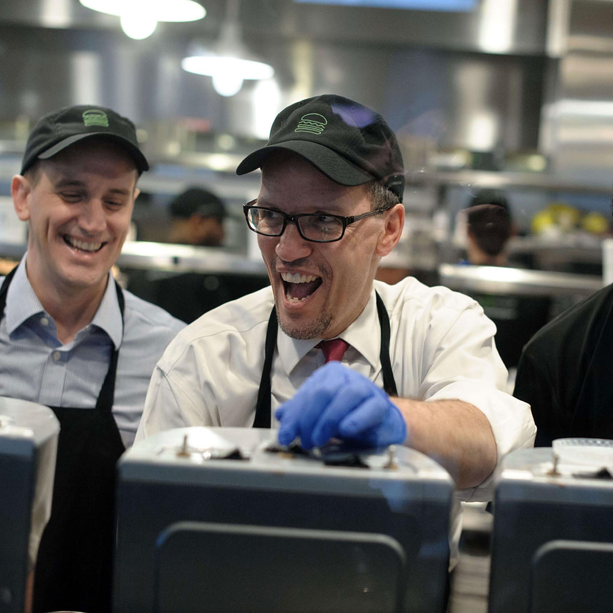 Labor Secretary Thomas Perez and Shake Shack CEO Randy Garutti laugh with an employee helping Perez make a milkshake as he toured a Shake Shack restaurant in Washington on March 21, 2014 to promote raising the federal minimum wage.