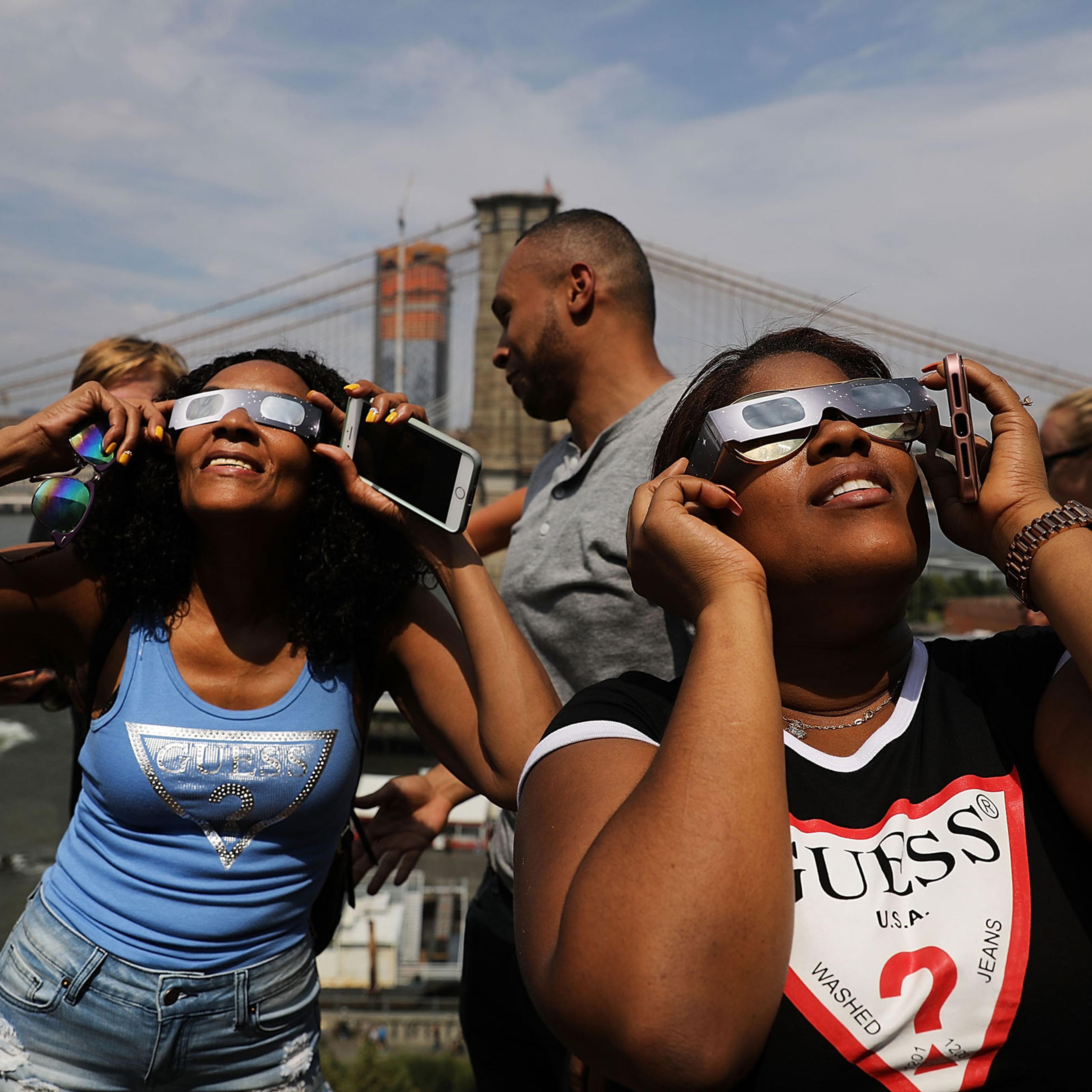People watch a partial solar eclipse from the roof deck at the 1 Hotel Brooklyn Bridge in New York City, on August 21, 2017.