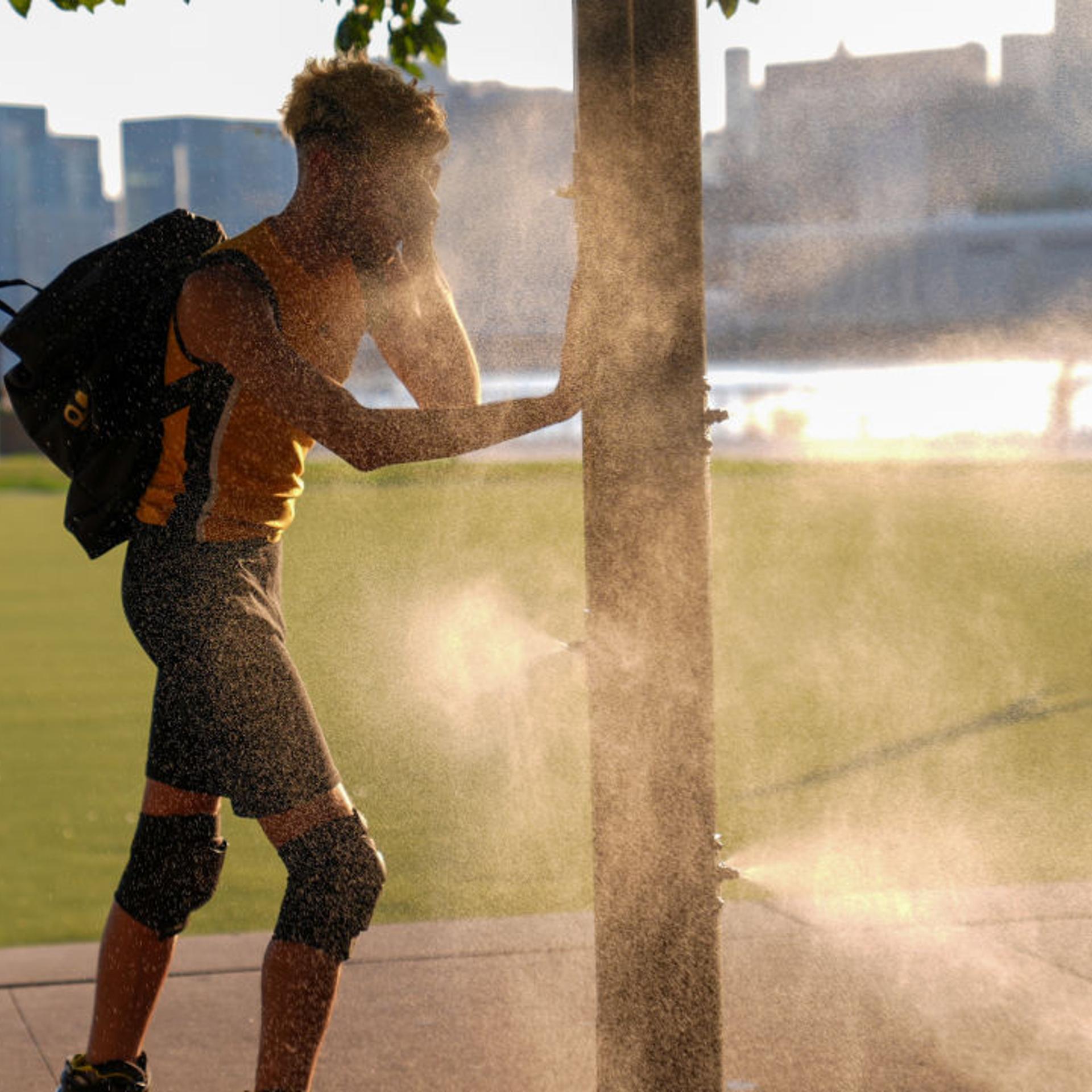 A man tries to cool off with a sprinkler that helps people cool off in New York City on July 15, 2024.