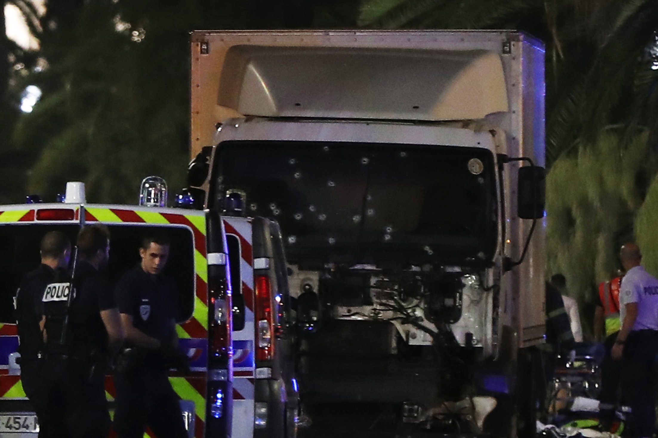 Police officers stand near a van, with its windscreen riddled with bullets, that tore into a crowd leaving a fireworks display in the French Riviera town of Nice on July 14, 2016. At least 70 people were killed in the French city of Nice on Thursday afte