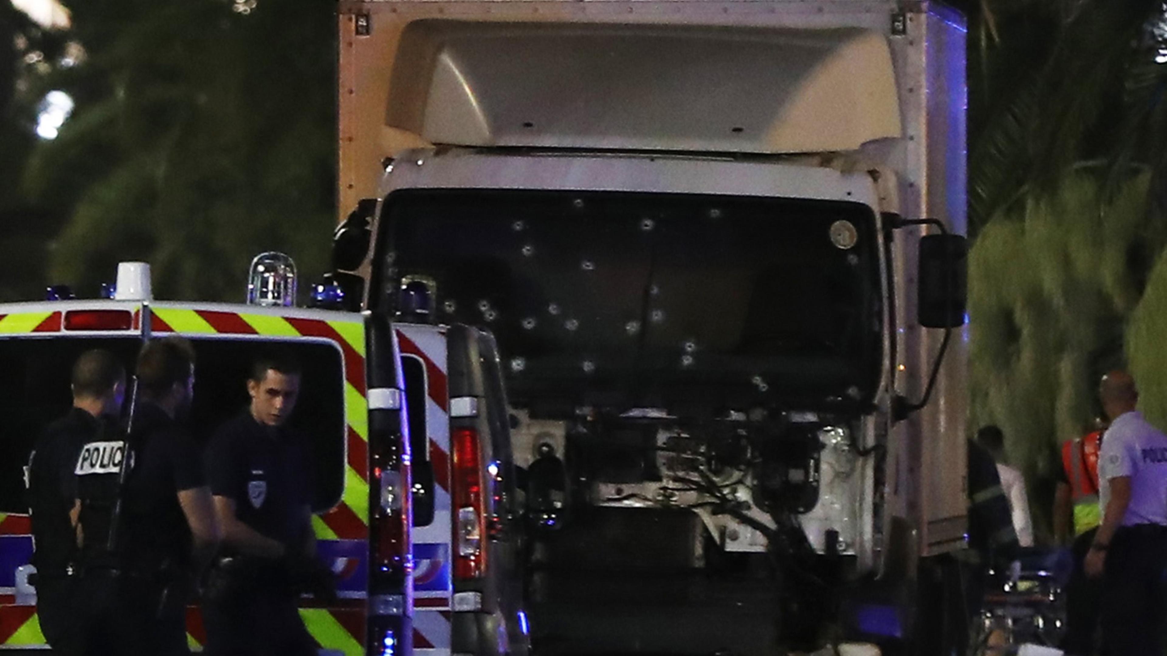 Police officers stand near a van, with its windscreen riddled with bullets, that tore into a crowd leaving a fireworks display in the French Riviera town of Nice on July 14, 2016. At least 70 people were killed in the French city of Nice on Thursday afte