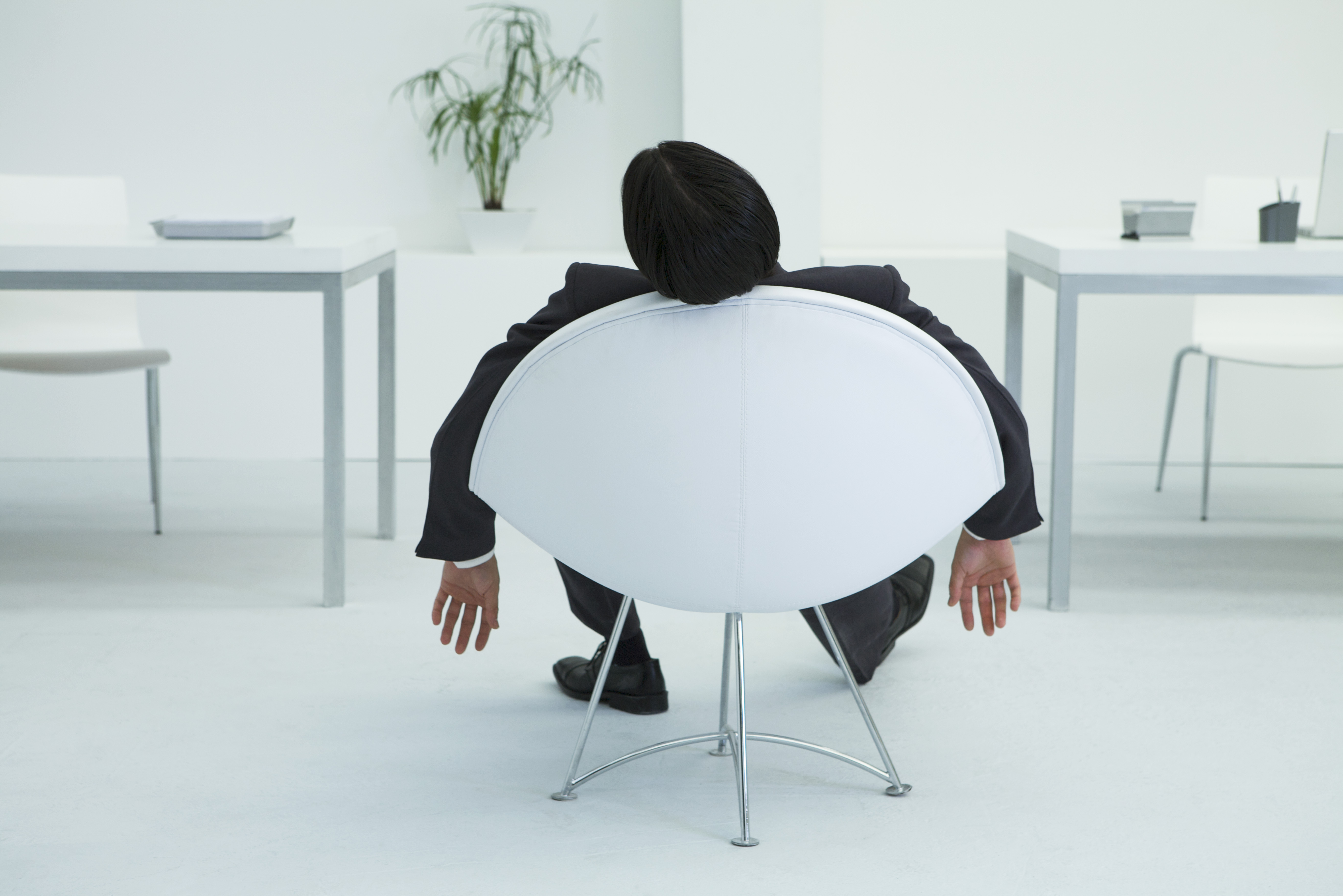 Businessman napping in chair in office, rear view TIME health stock