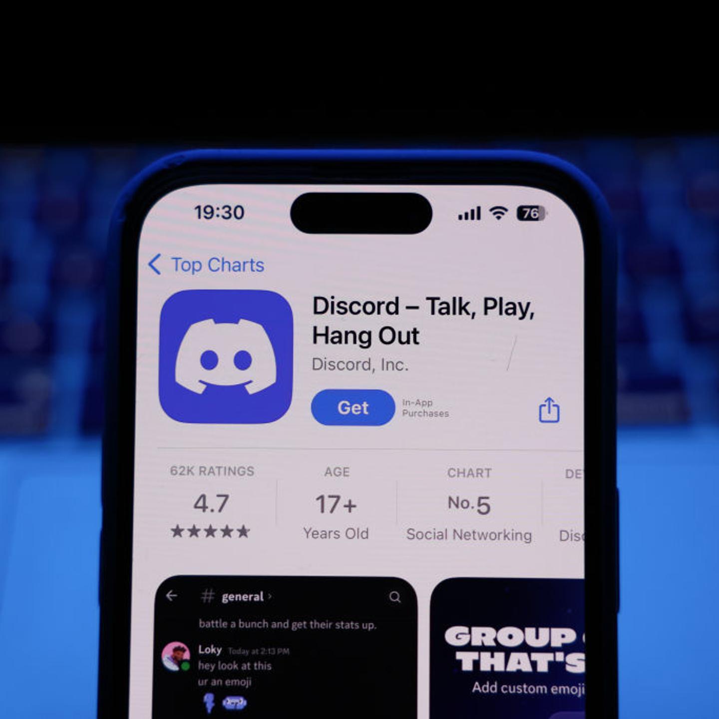 A laptop keyboard and Discord on the App Store are displayed on a phone screen on March 17, 2025.