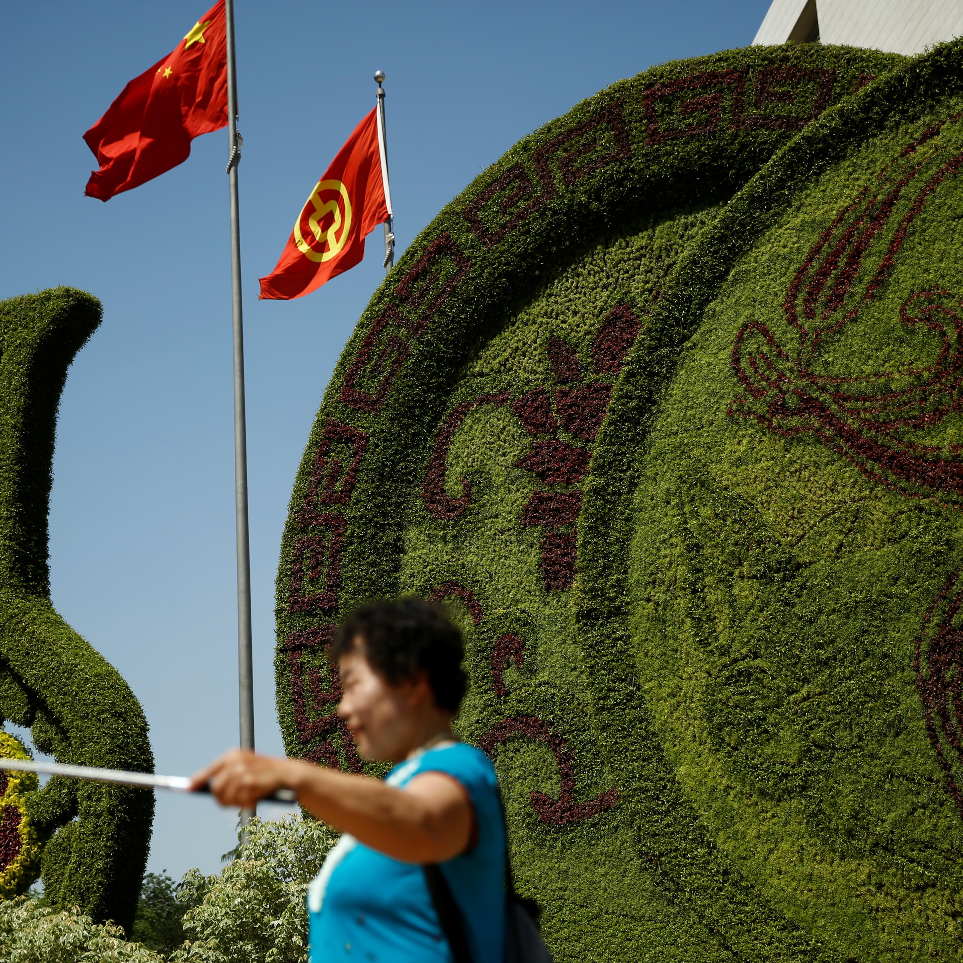 A woman takes pictures in front of a flower display set up ahead of the Belt and Road Forum in central Beijing