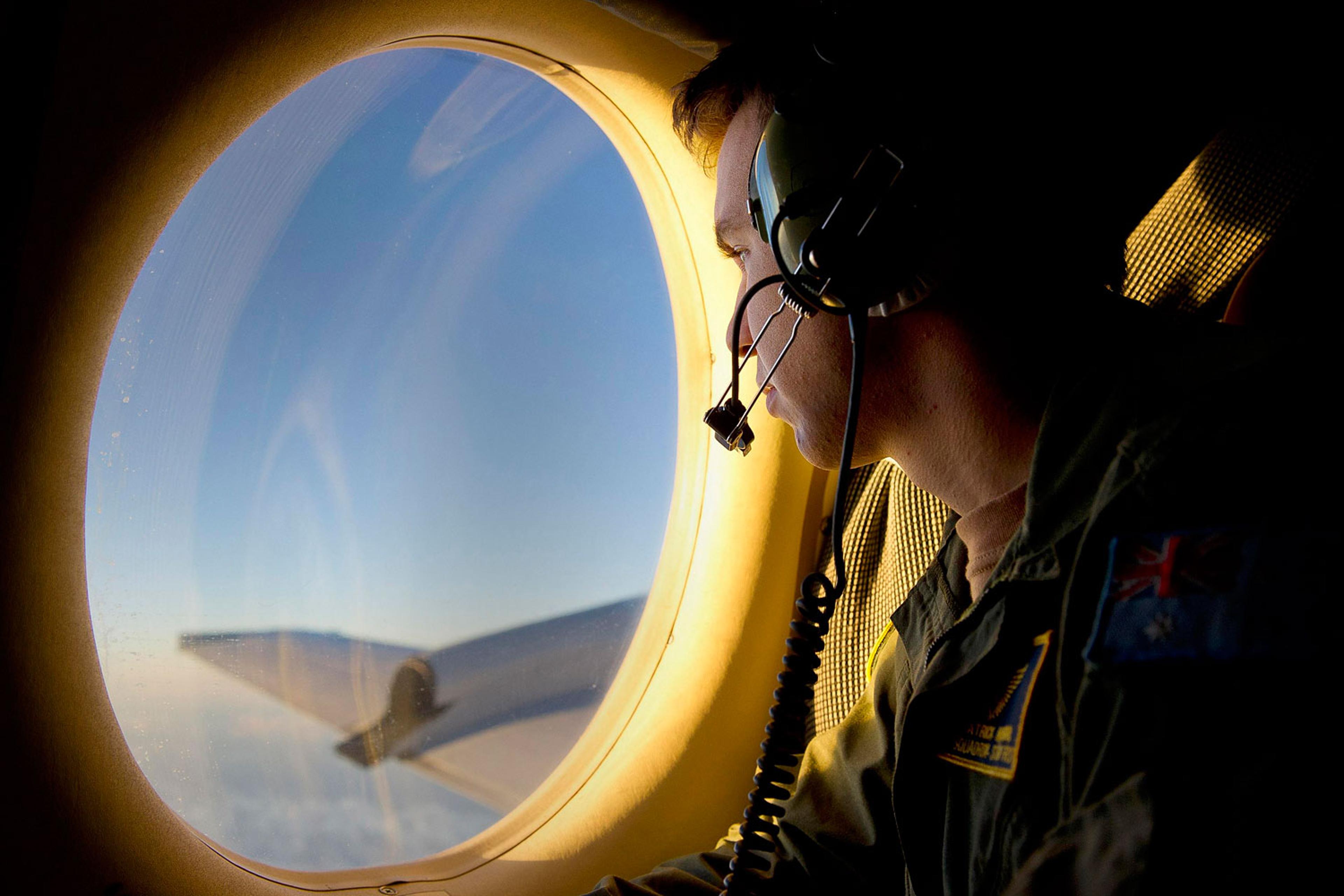 Royal Australian Air Force (RAAF) Airborne Electronics Analyst Sergeant Patrick Manser looks out of an observation window aboard a RAAF AP-3C Orion aircraft during the search in the southern Indian Ocean for debris from the missing Malaysian Airlines fli
