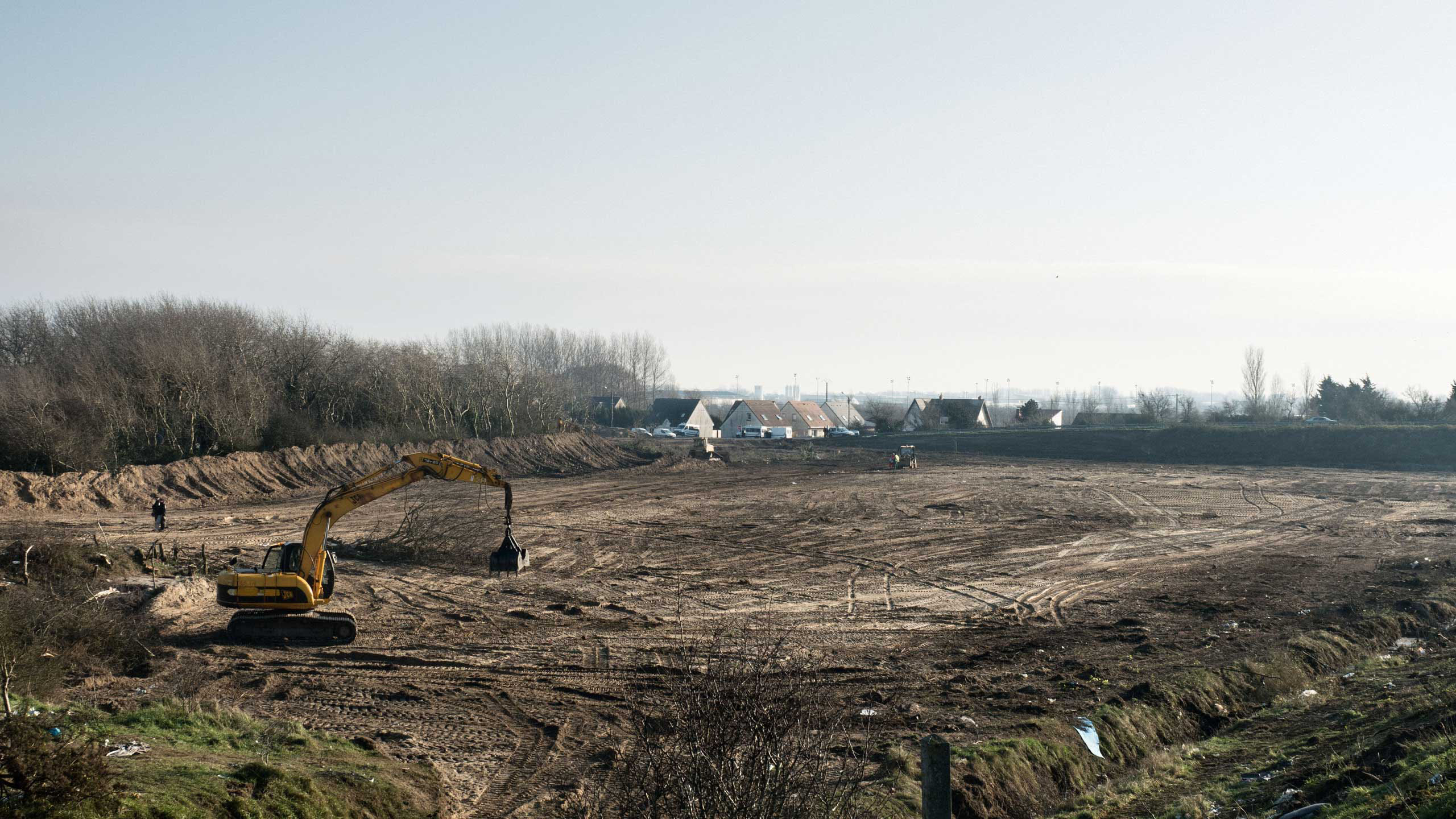 A bulldozer protected by riot police has begun carving a path towards the "jungle" camp in Calais, France after authorities told the migrants to move into new housing so the tent camp can be destroyed. French authorities want to create a 100-meter buffer
