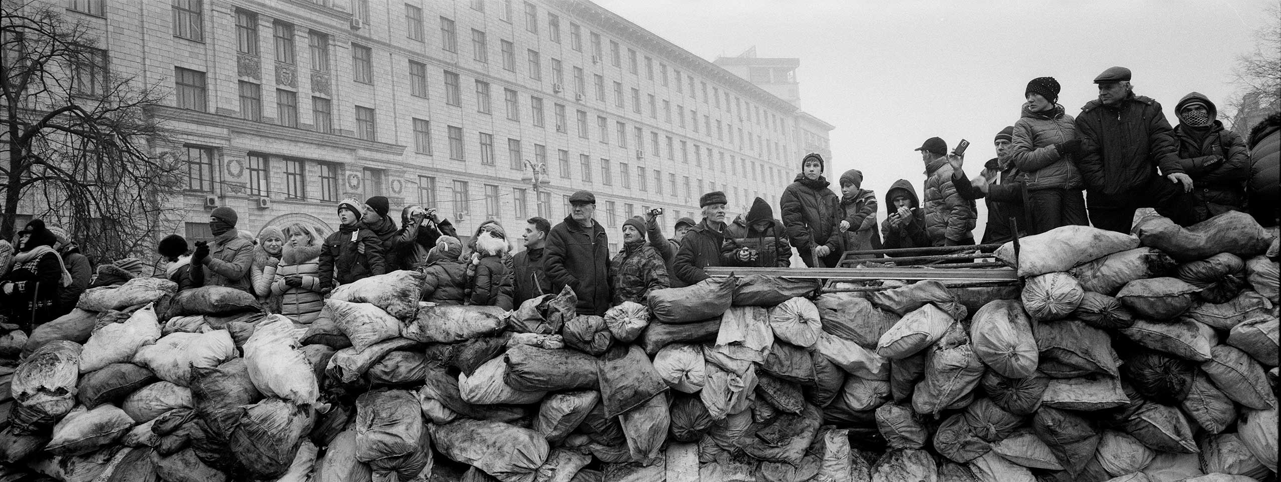 Ukrainian civilians stand behind a barricade as they watch at Riot police lines near the Maidan square in Kiev, 2014. From the
series: Barricades, Kiev, Ukraine, 2014. 