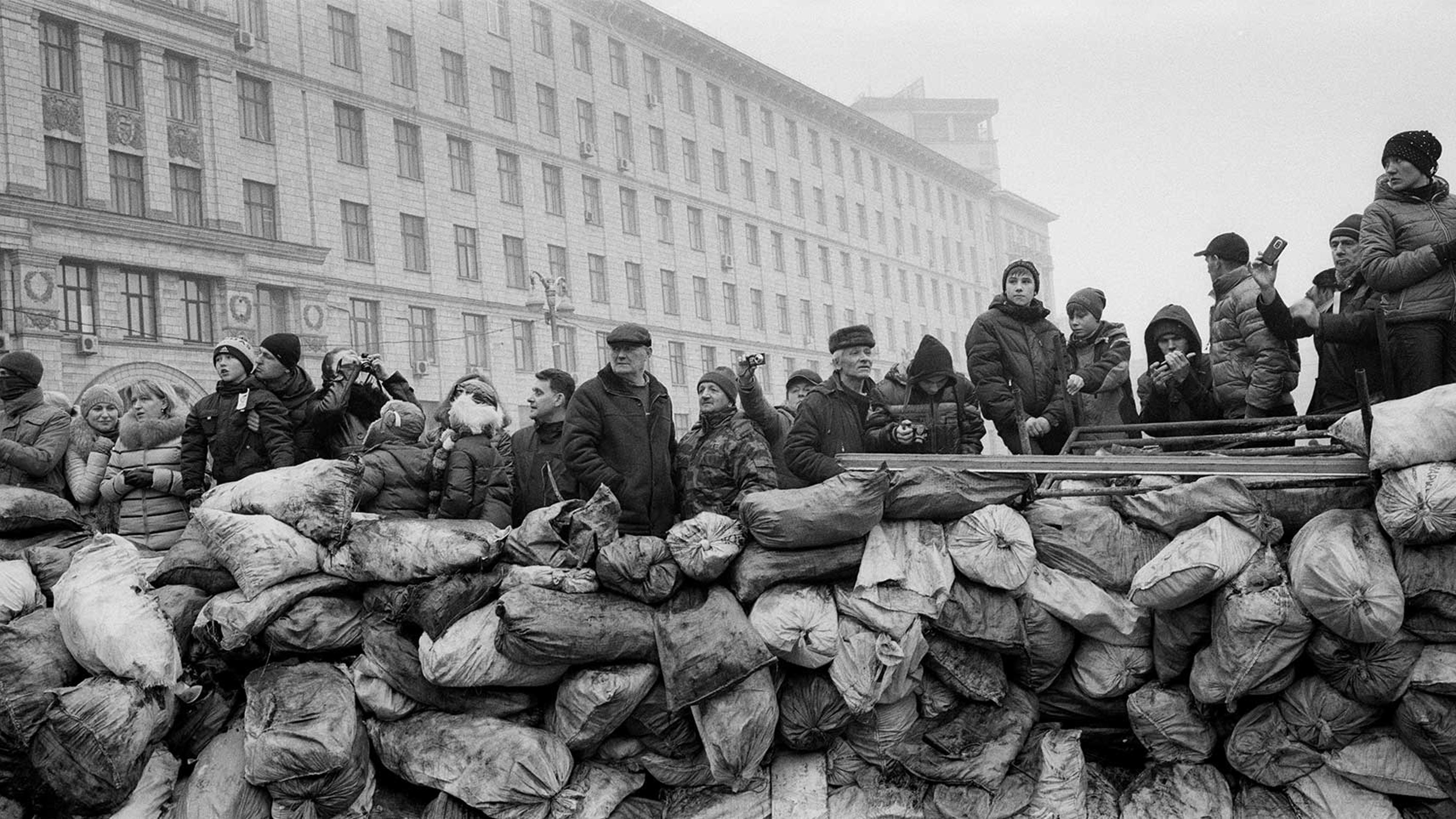 Ukrainian civilians stand behind a barricade as they watch at Riot police lines near the Maidan square in Kiev, 2014. From the
series: Barricades, Kiev, Ukraine, 2014.