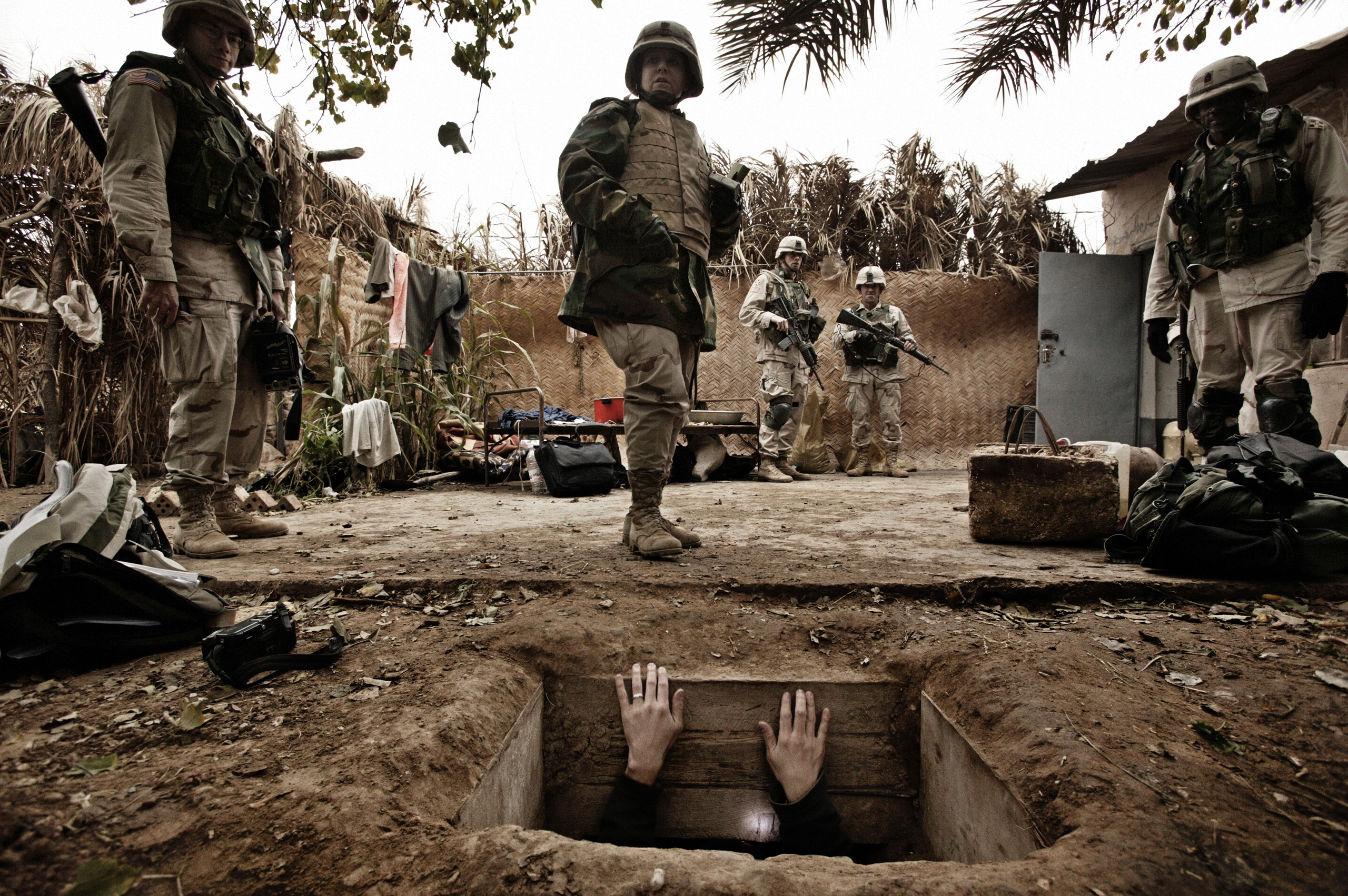 A jounalist climbs out of the hole where toppled dictator Saddam Hussein was captured in Ad Dawr, Iraq, near his hometown of Tikrit, Dec. 15, 2003.
