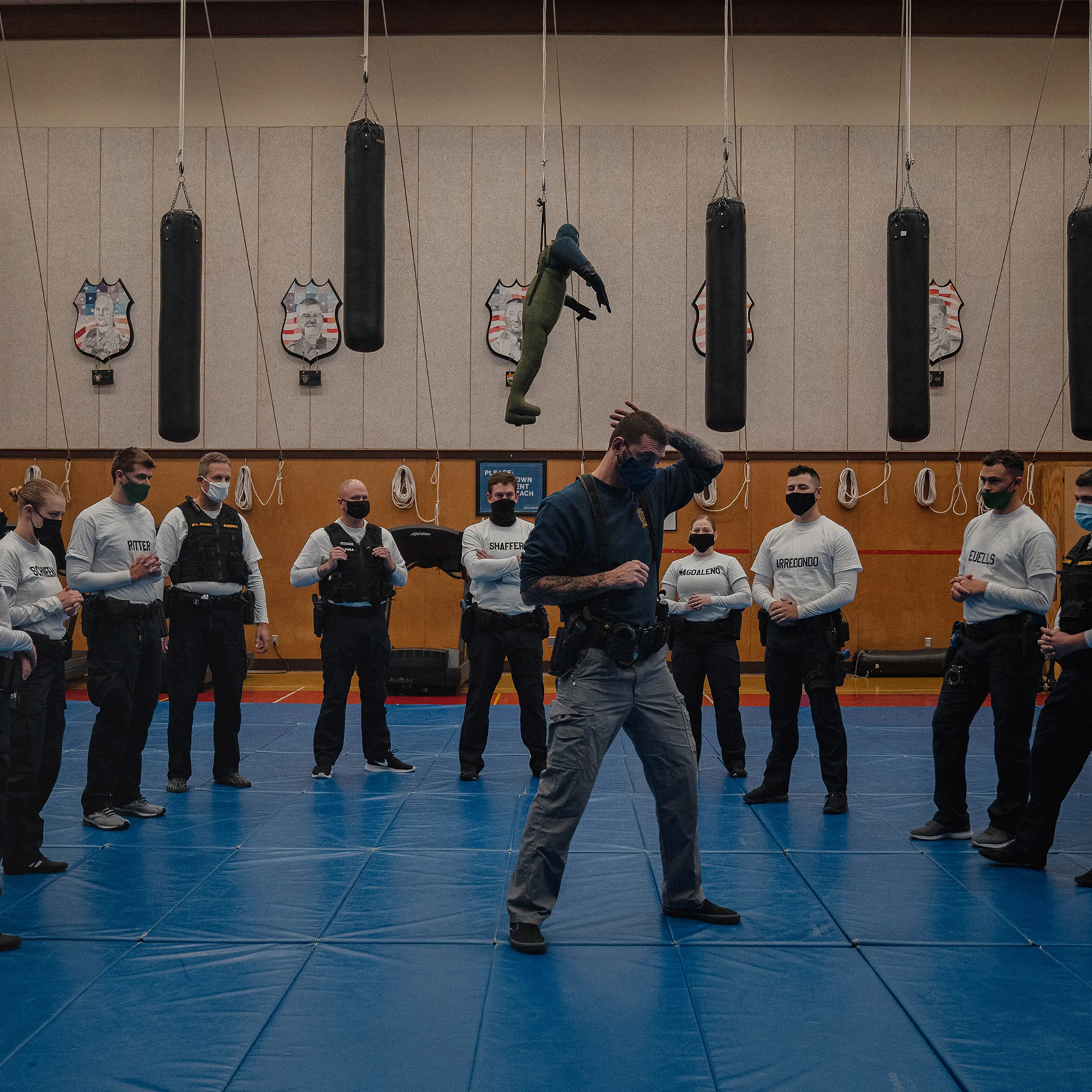 With punching bags and dummies overhead, instructor Javier Sola teaches frisking and handcuffing methods to police recruits at the Washington State Criminal Justice Training Commission facility in Burien, Wash., on Oct. 22. Washington State requires all